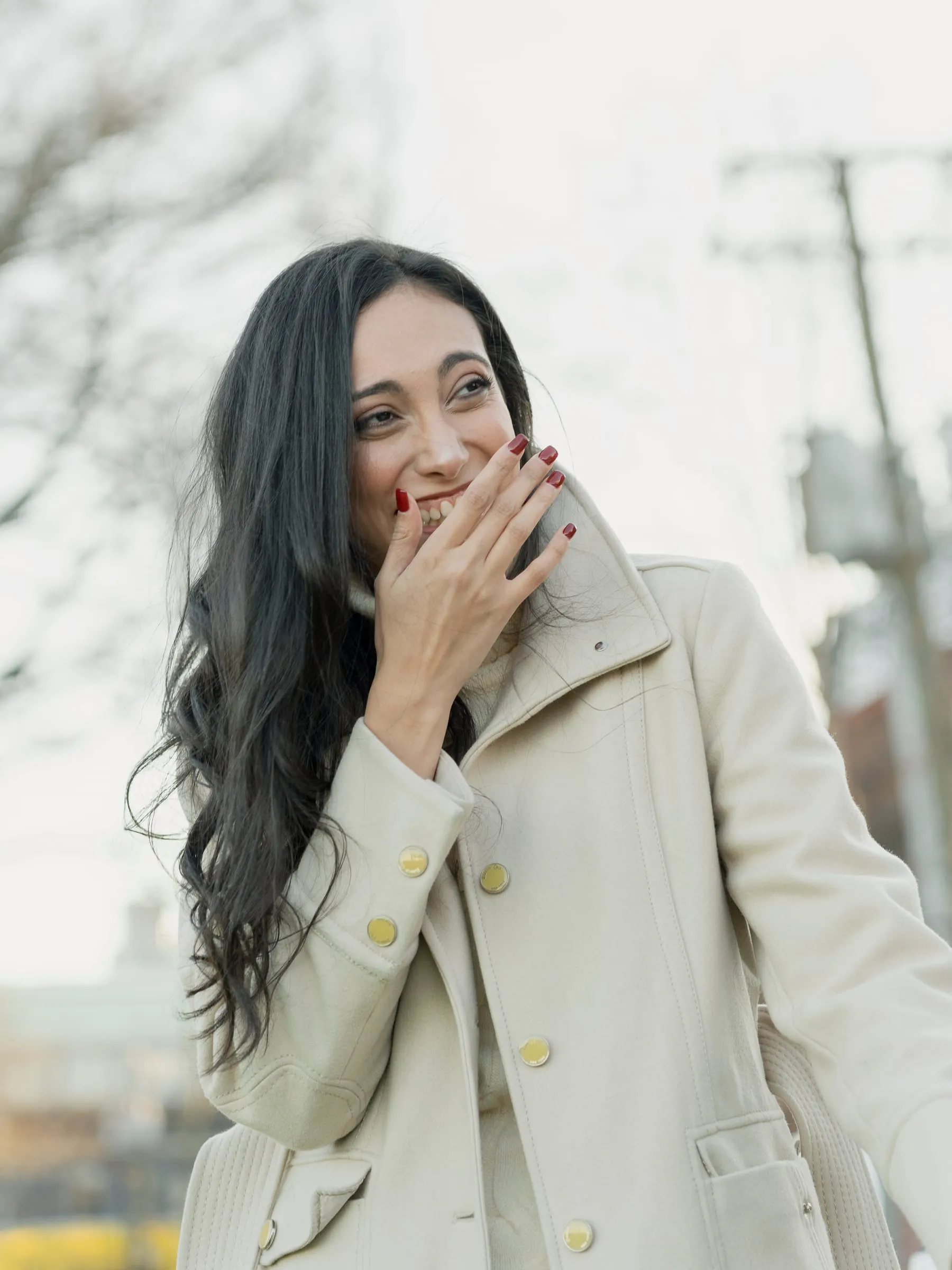 Merona smiling through raised fingers, overwhelmed, in the soft winter light