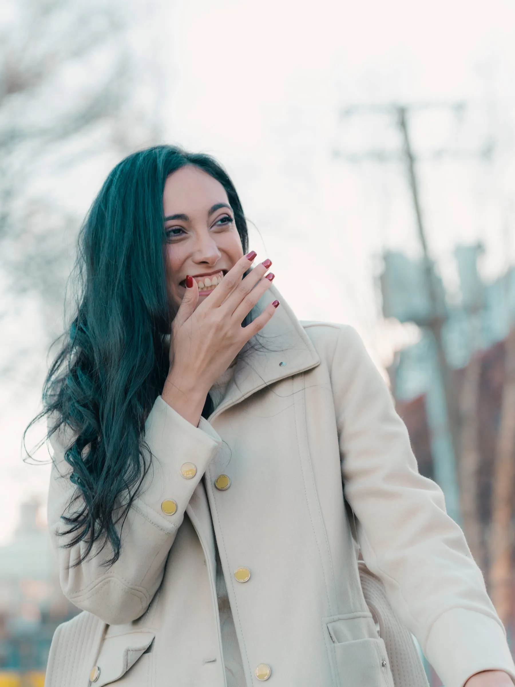 Merona beaming with a hand at the lips, bare trees and Old Town rooftops in the background