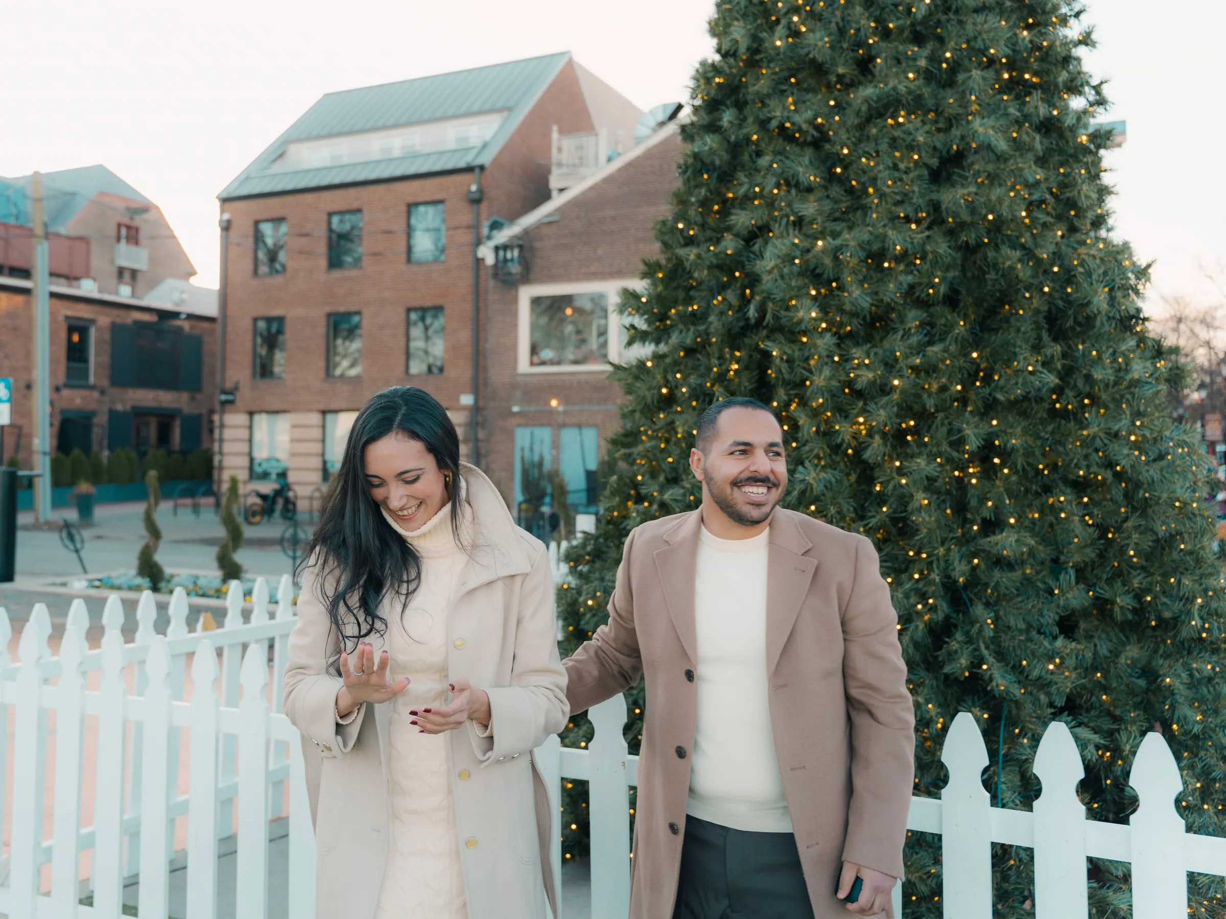 Merona looking down at the new ring as Abanoub smiles alongside by the Christmas tree