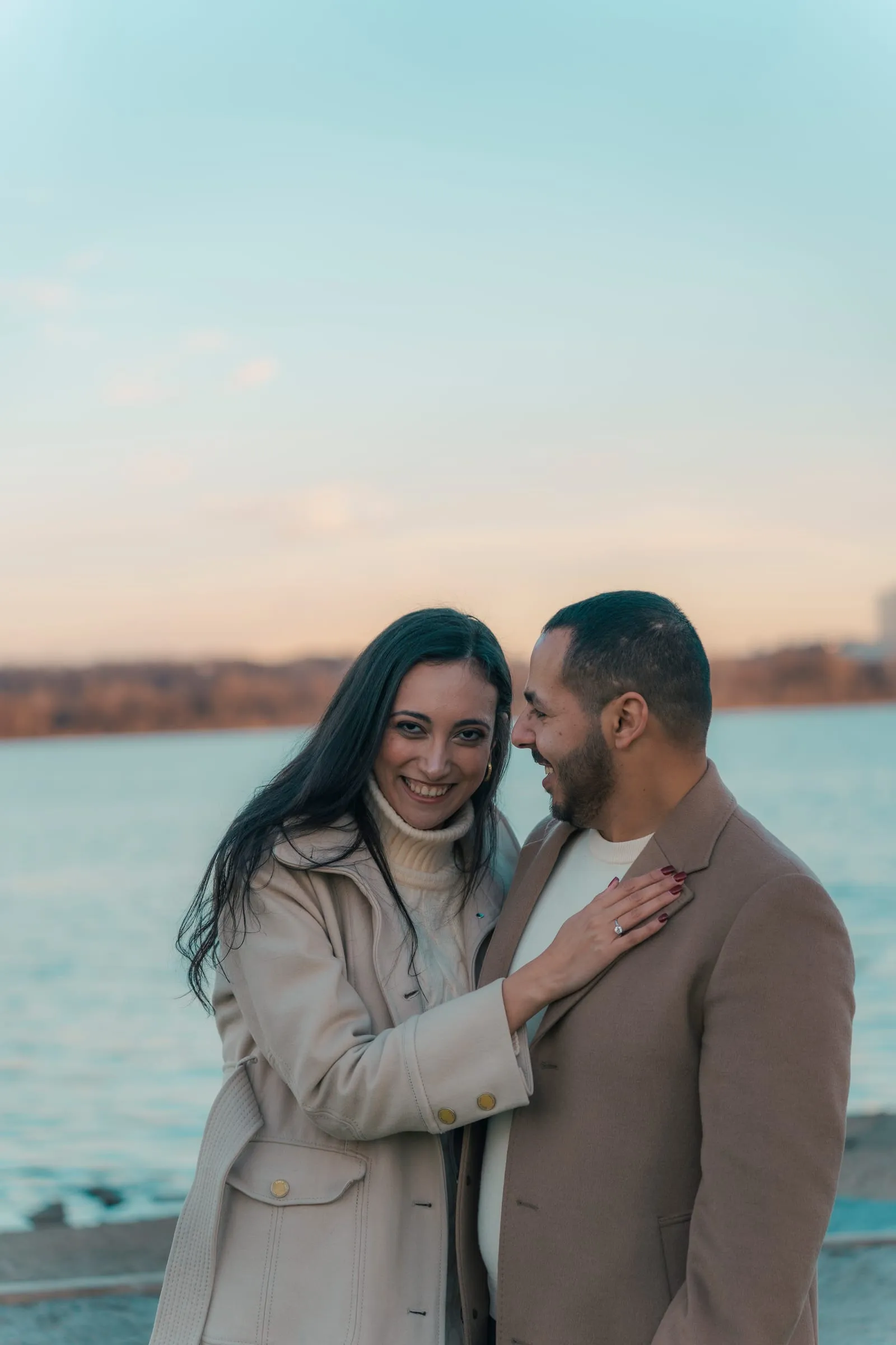 Merona laughing and leaning into Abanoub on the Potomac waterfront at sunset