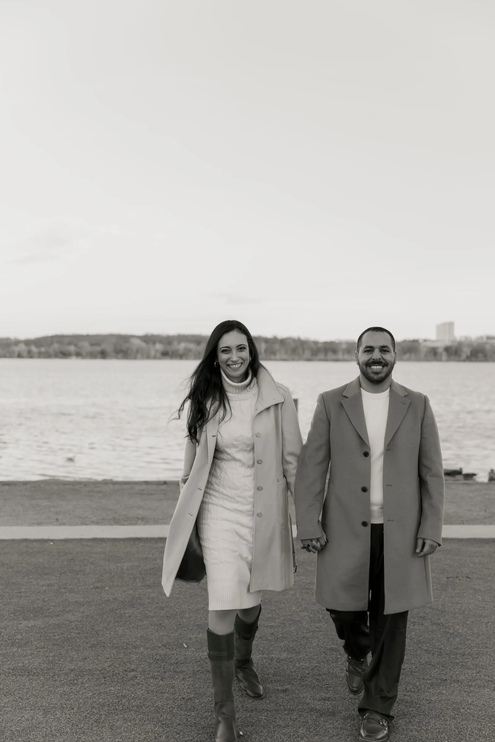 Black and white photo of Abanoub and Merona walking hand in hand along the river