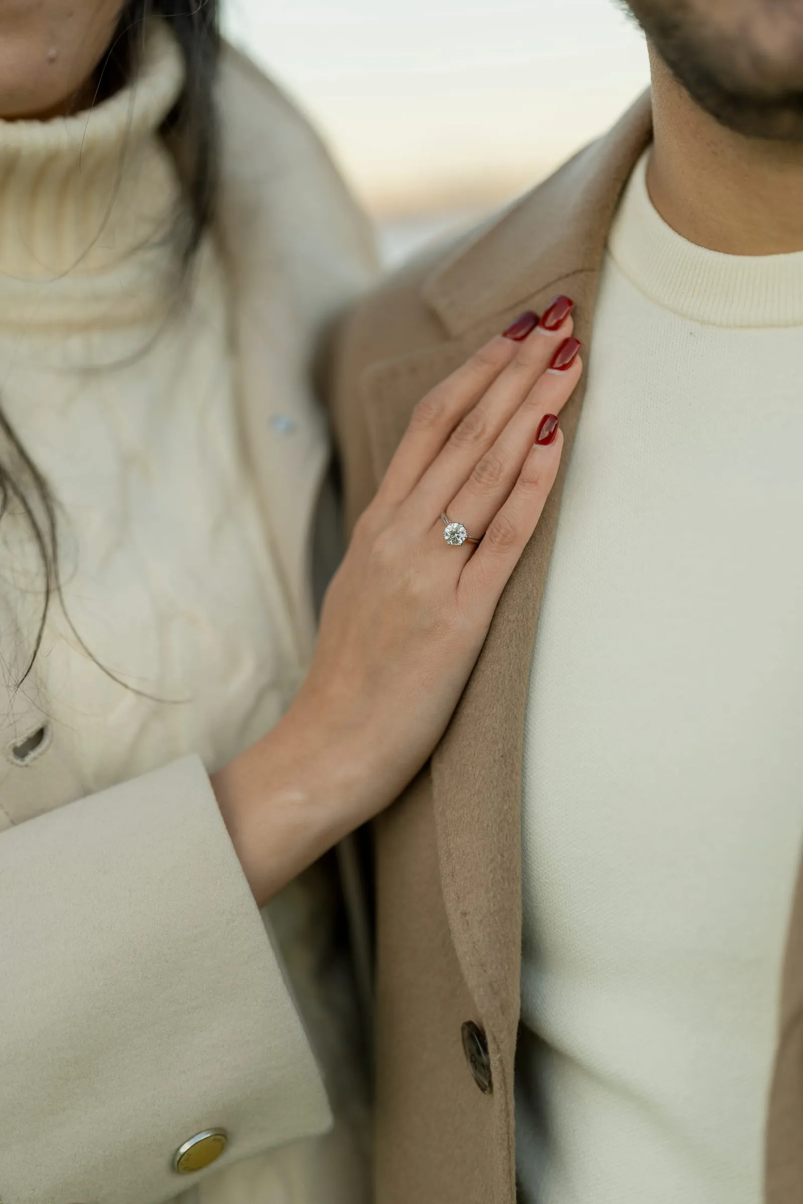 Close-up of Merona's hand and engagement ring resting on Abanoub's coat