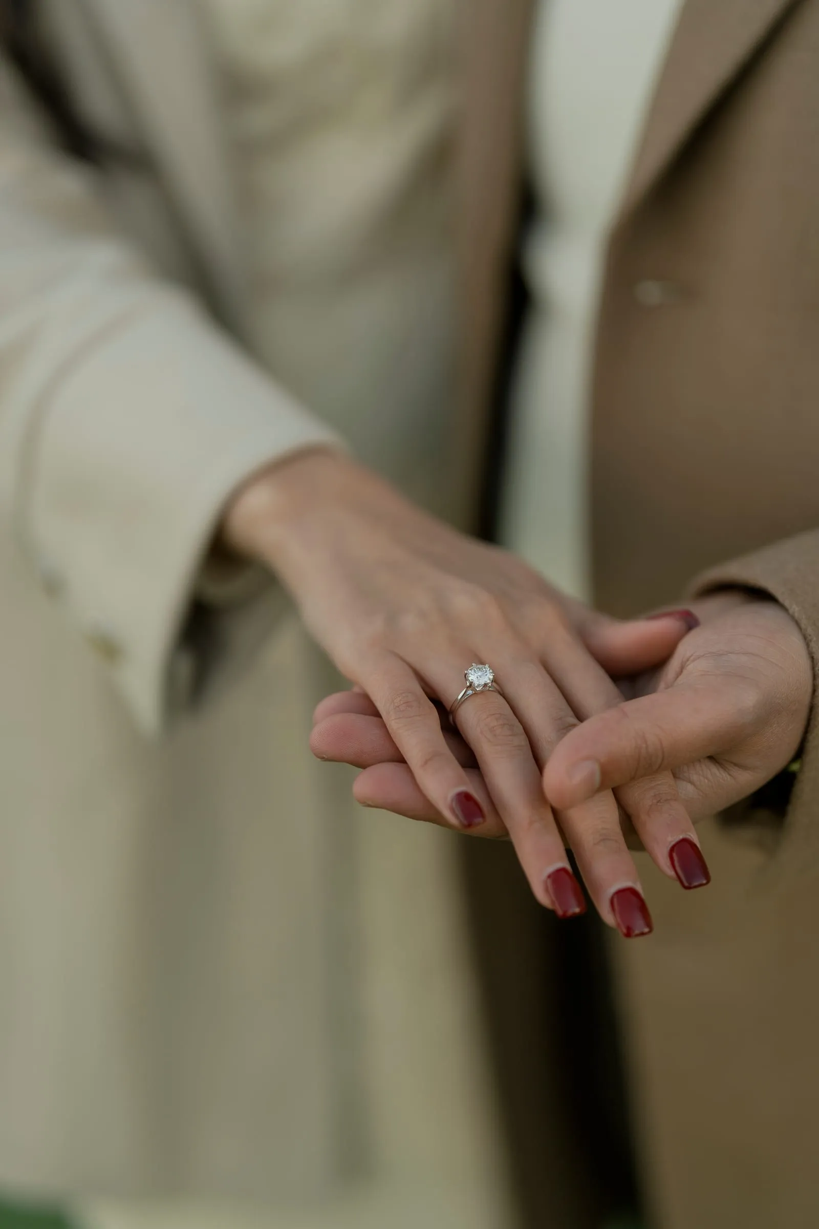 Merona's engagement ring on a hand laid over Abanoub's, their winter coats softly blurred