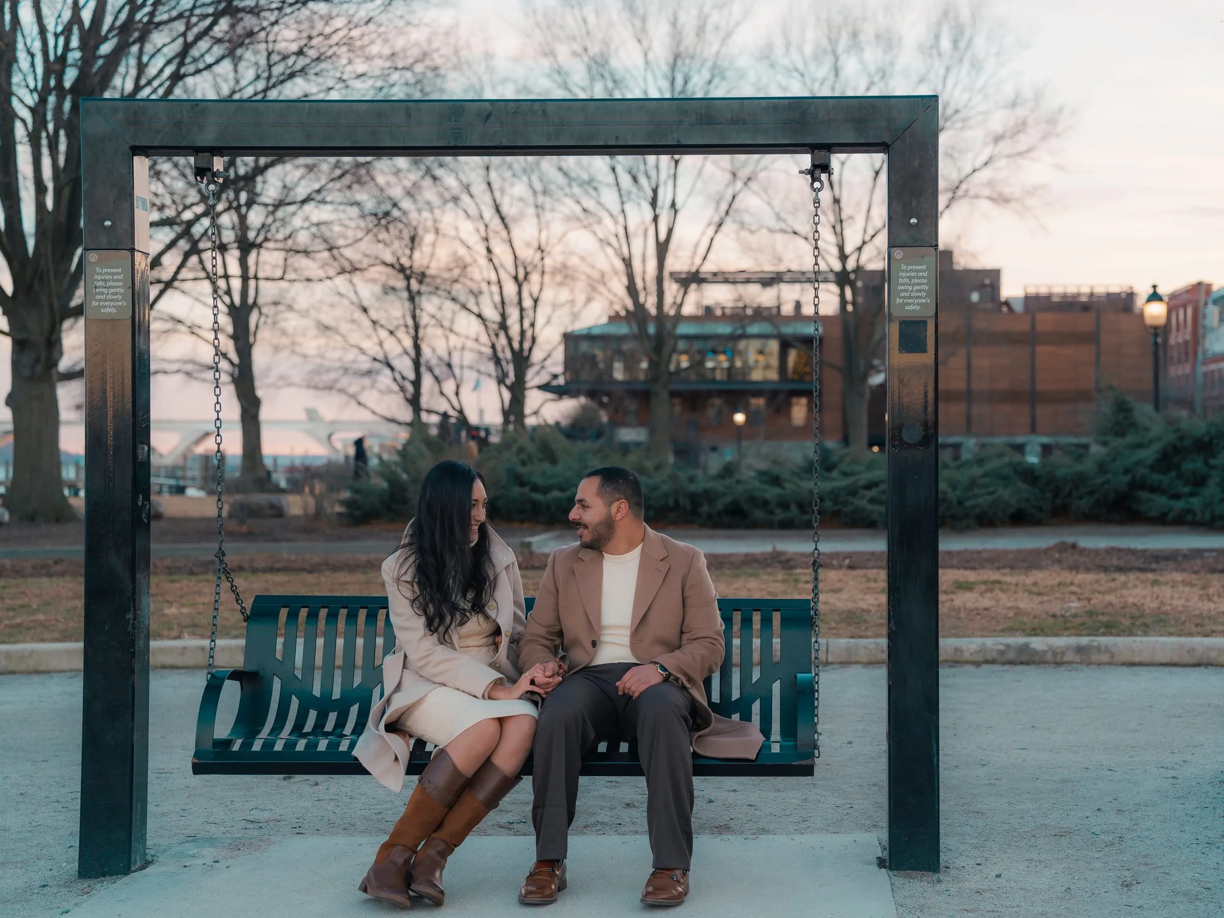 Abanoub and Merona sitting close on a waterfront swing in Old Town Alexandria