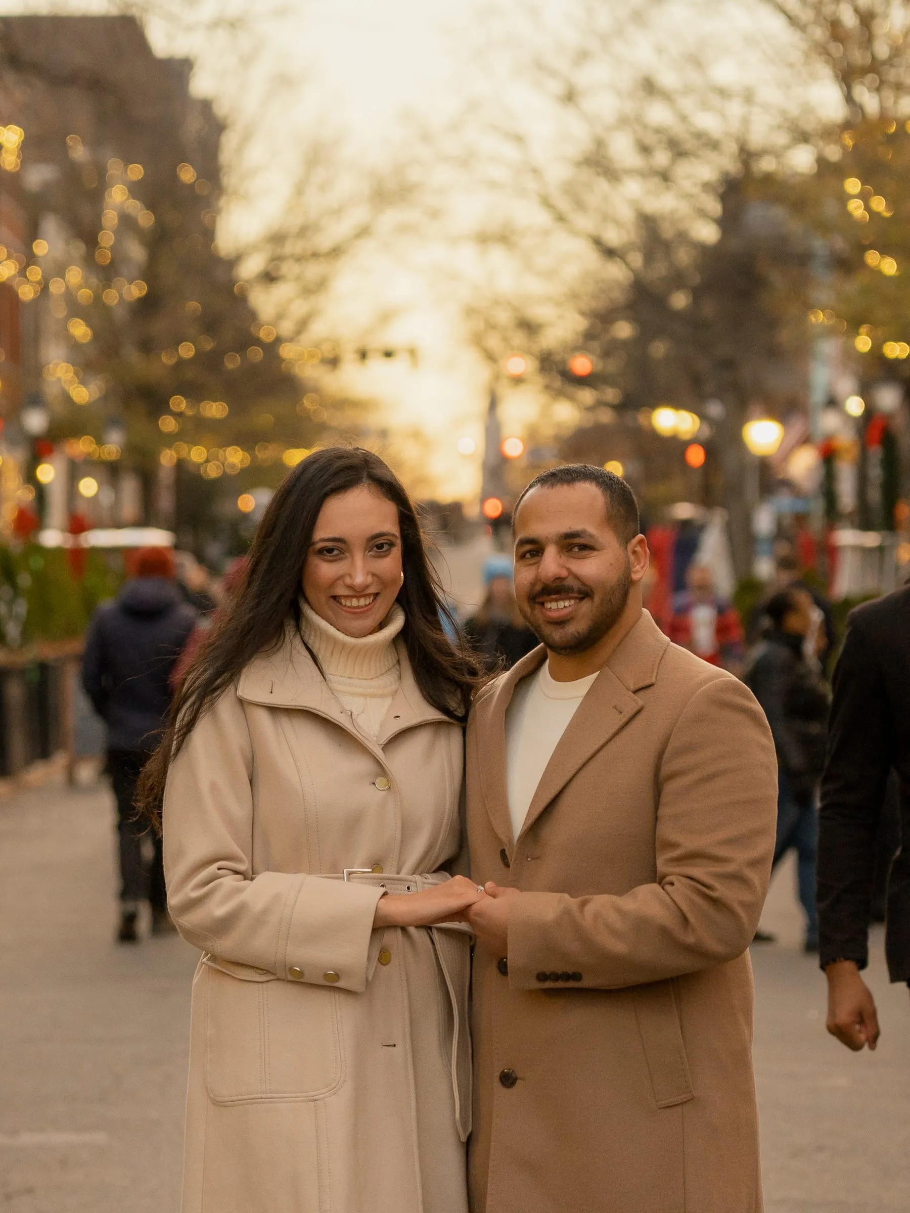 Abanoub and Merona smiling close together on a busy street glowing with holiday lights