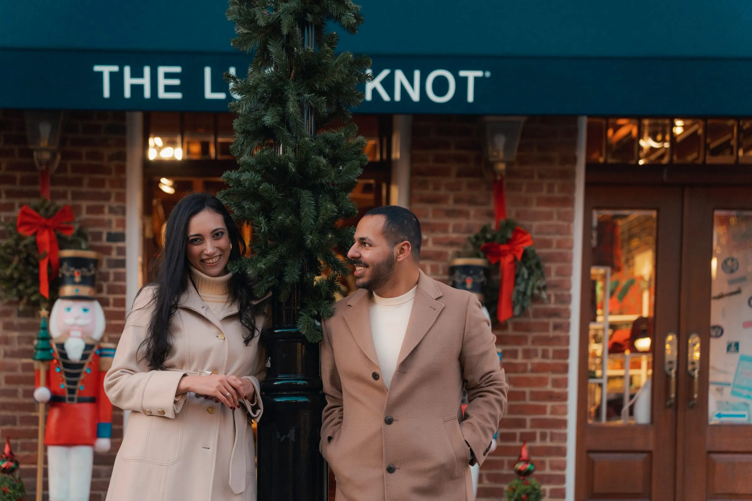 Merona smiling at the camera as Abanoub laughs alongside, nutcracker decorations by the door