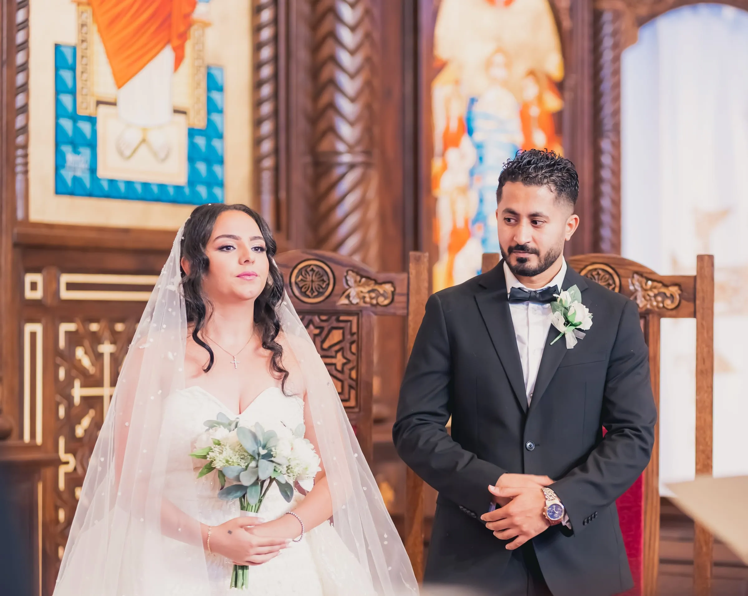Gina and Fady standing quietly at the altar, hands folded, during the ceremony