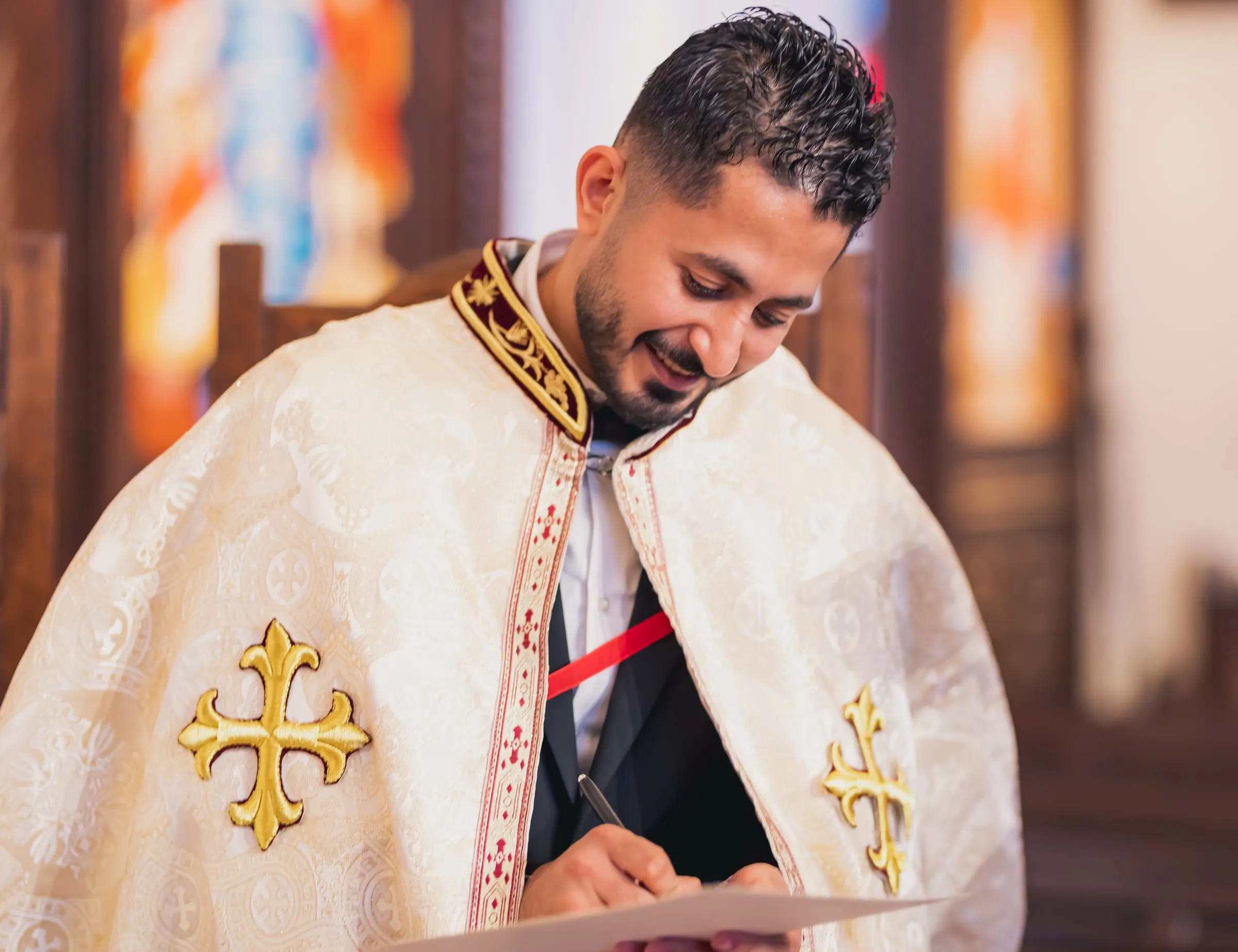 Fady signing the marriage certificate in an embroidered ceremonial robe