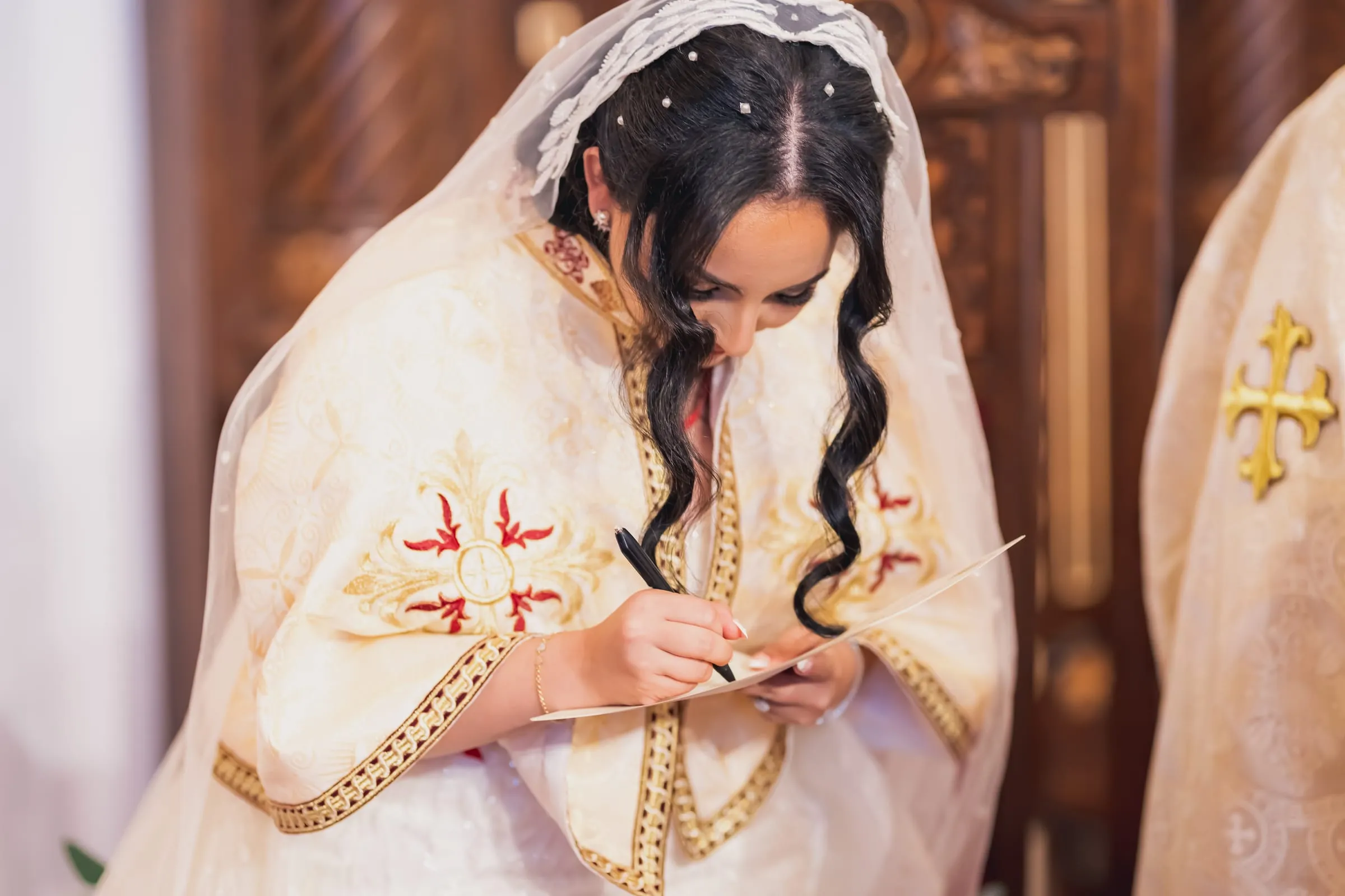 Gina signing the marriage certificate, the lace veil falling around Gina's face