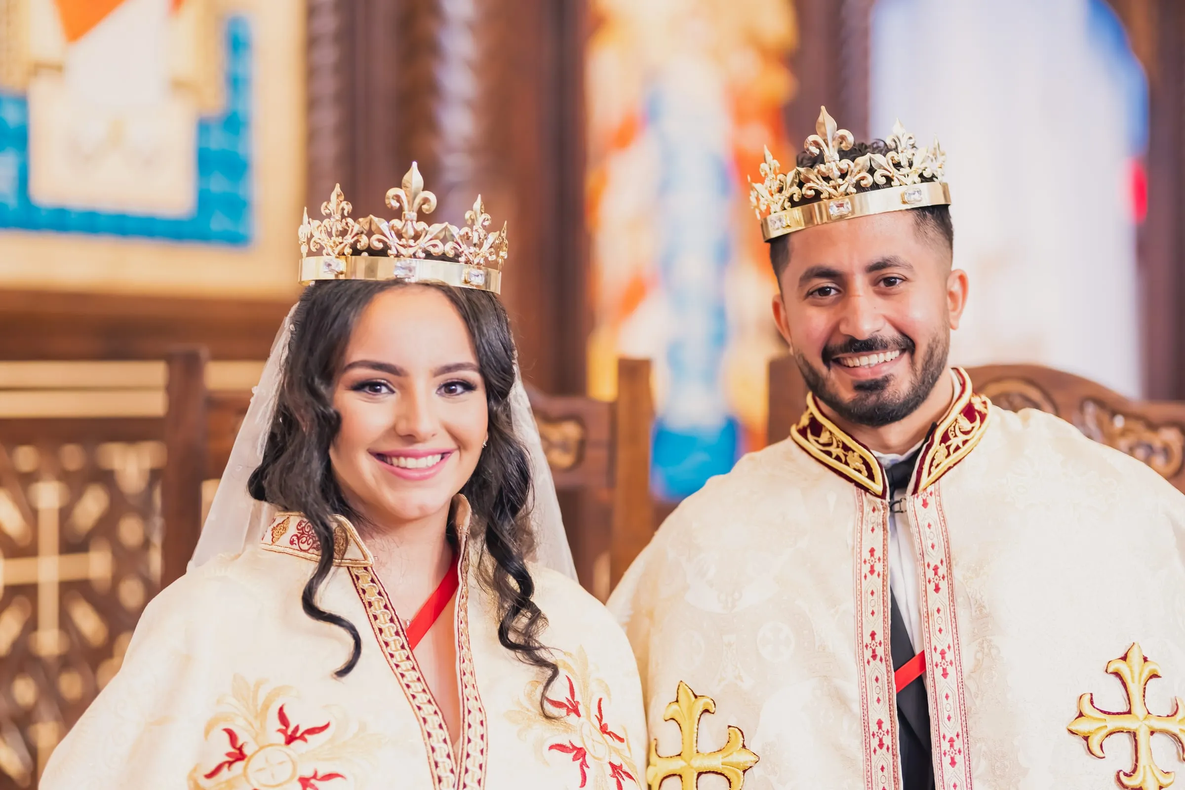 A close portrait of Gina and Fady crowned and smiling before the iconostasis