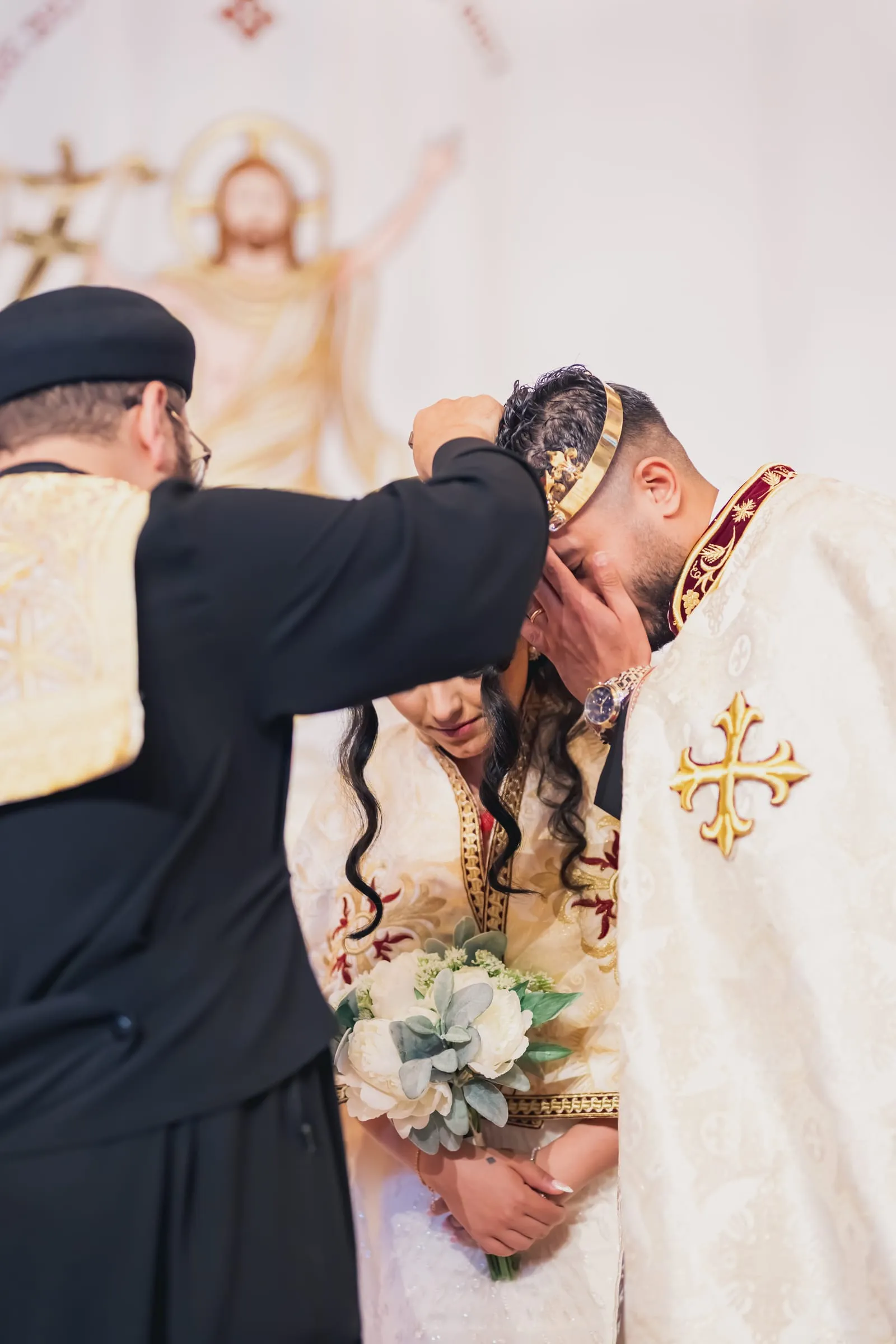 The priest blessing Gina and Fady as they bow their crowned heads together