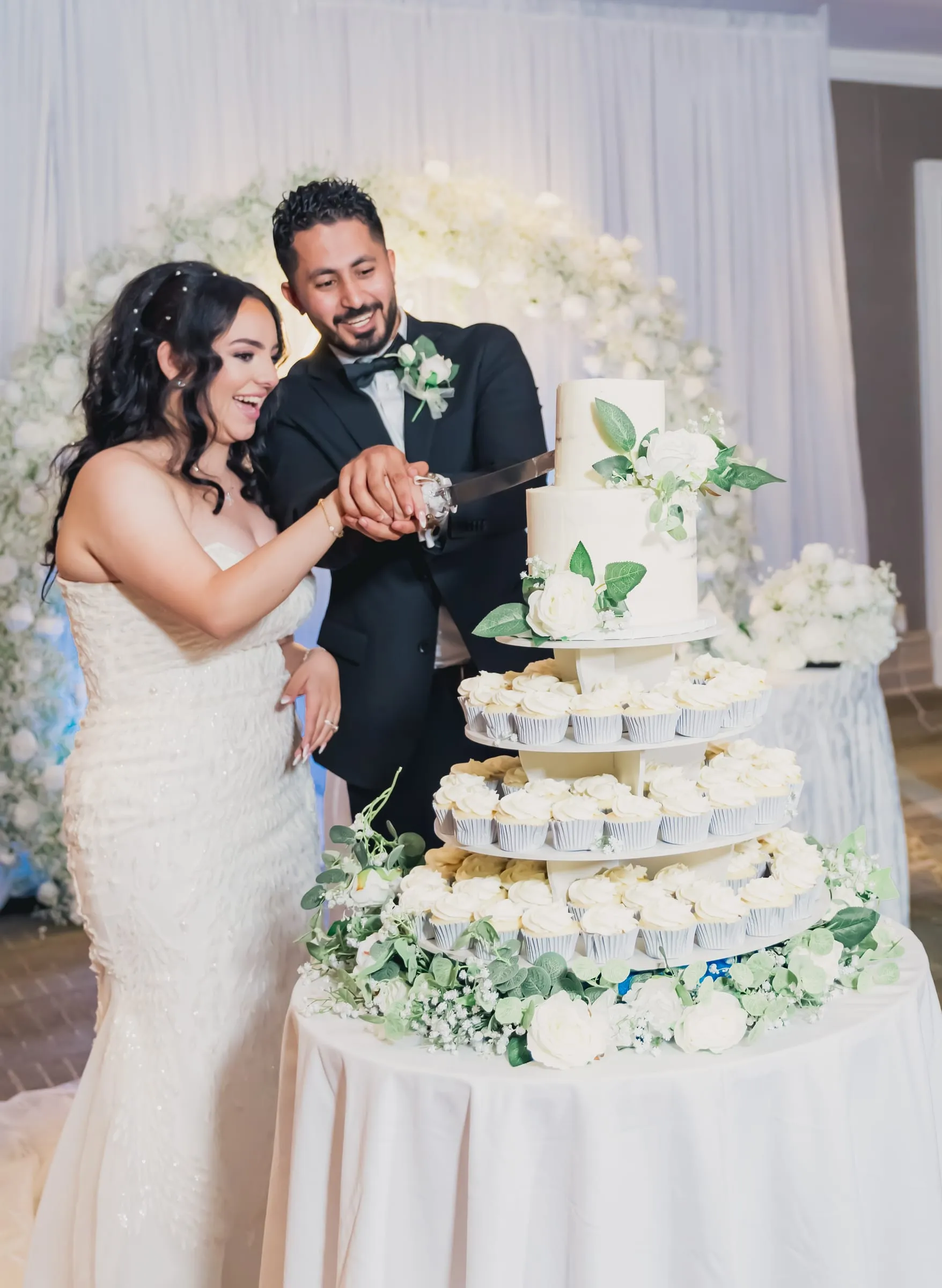 Gina and Fady laughing as they slice the wedding cake together