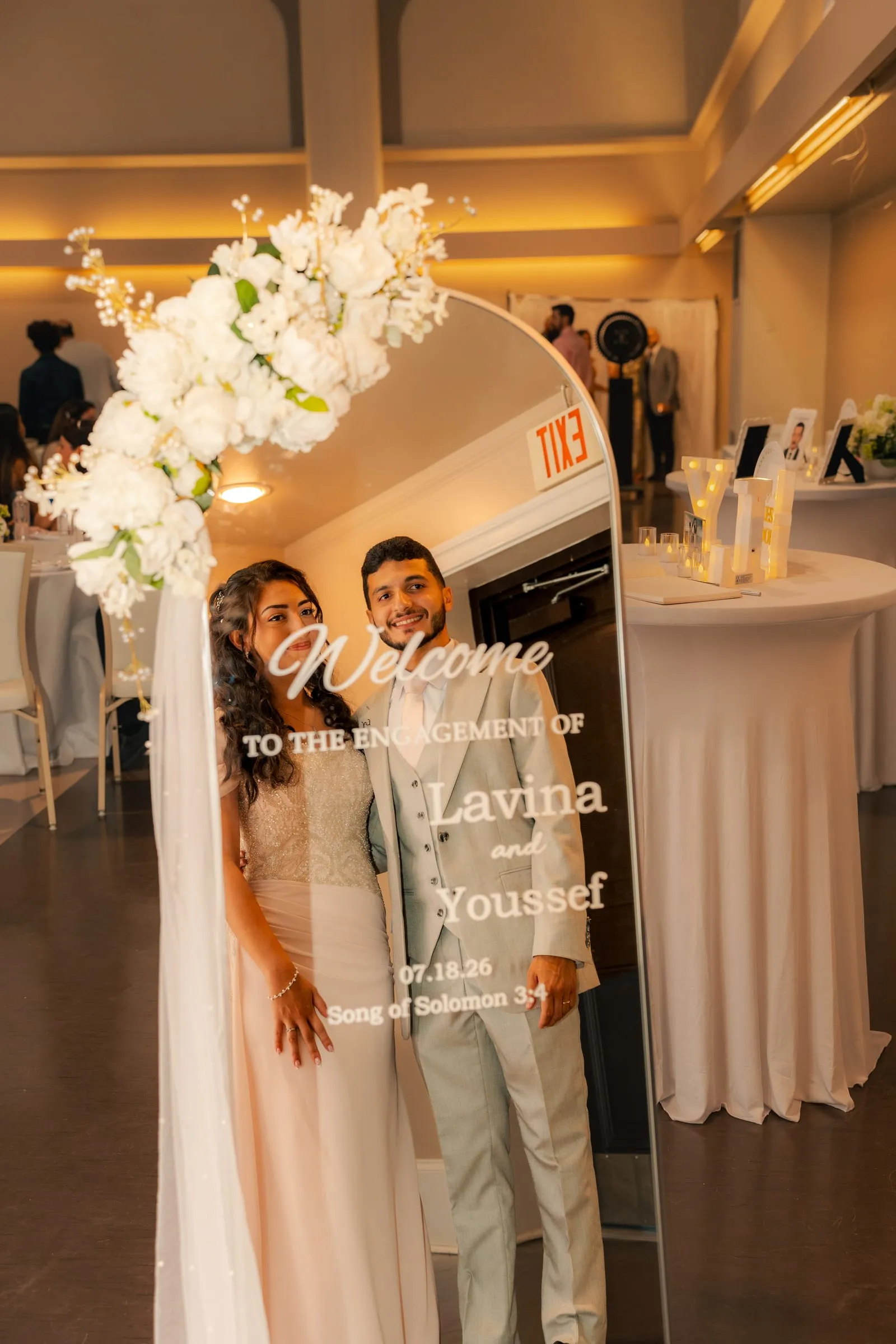 Lavina and Youssef arm in arm in front of the reception room at their Hampton, Virginia engagement celebration