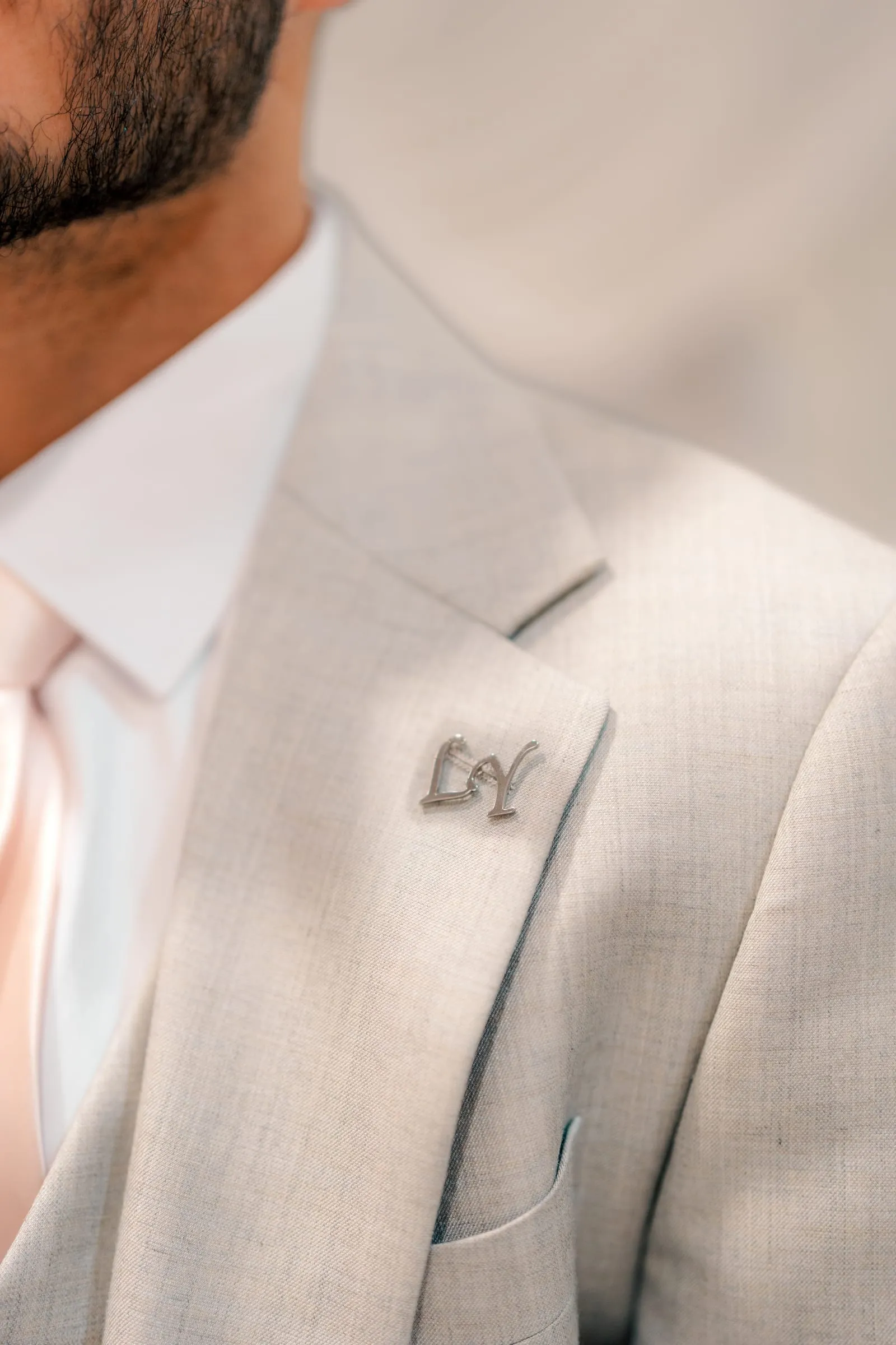 Close-up of Youssef's suit lapel with a silver LY monogram pin