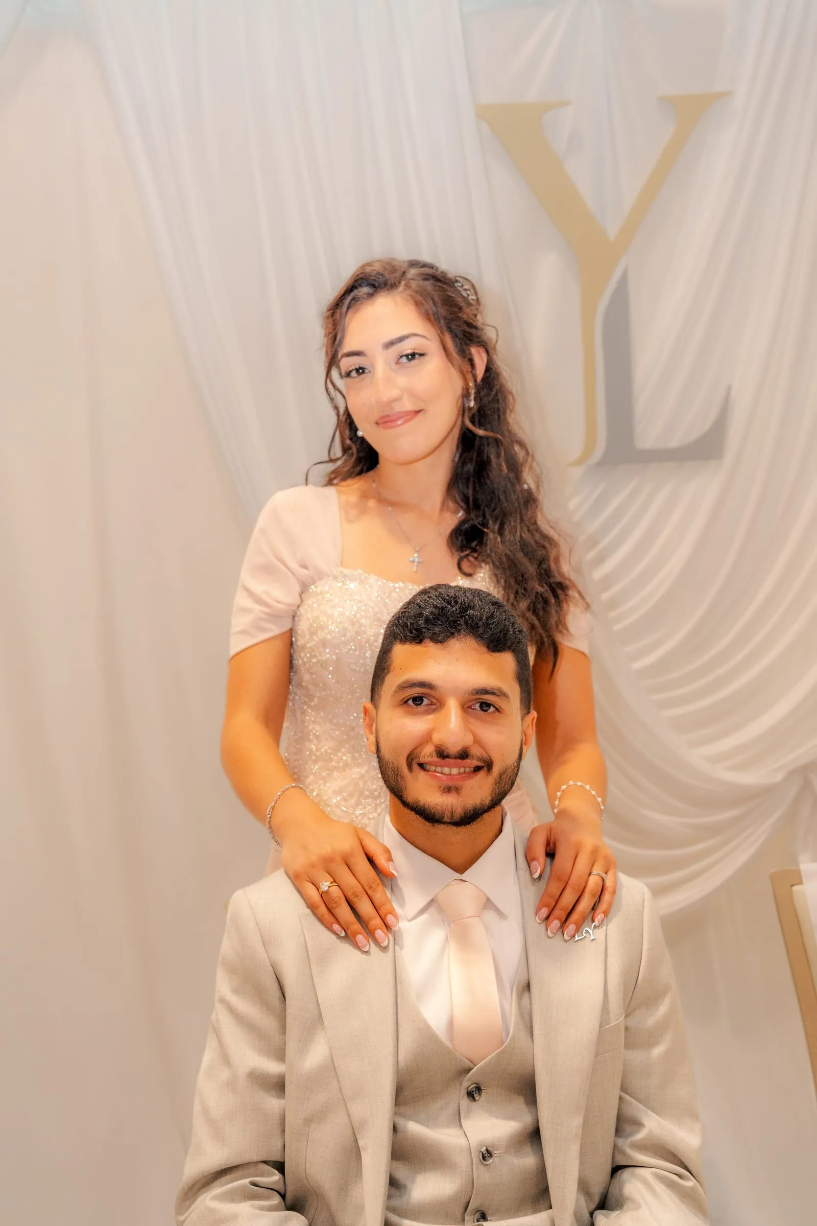 Lavina resting her hands on Youssef's shoulders, both smiling at the camera