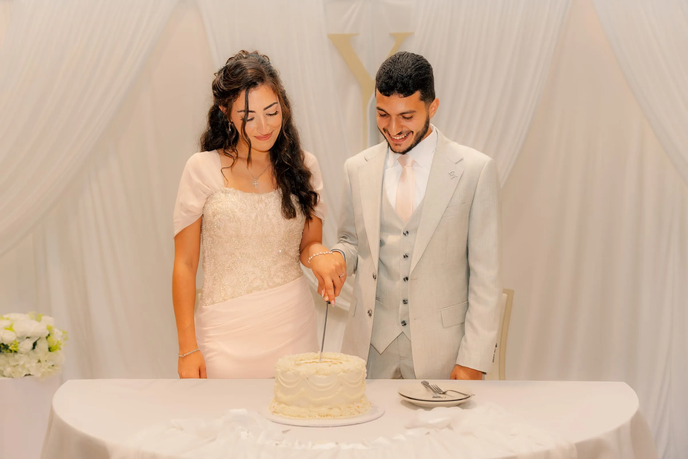 Lavina and Youssef smiling as they cut into the cake at their engagement celebration