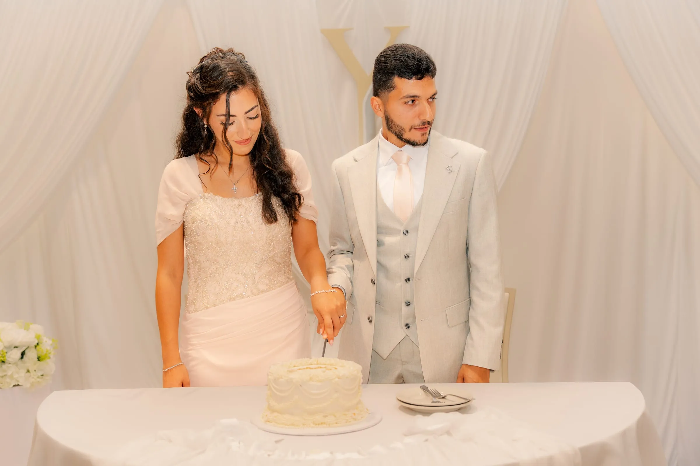 Youssef glancing away with a smile as Lavina cuts the engagement cake