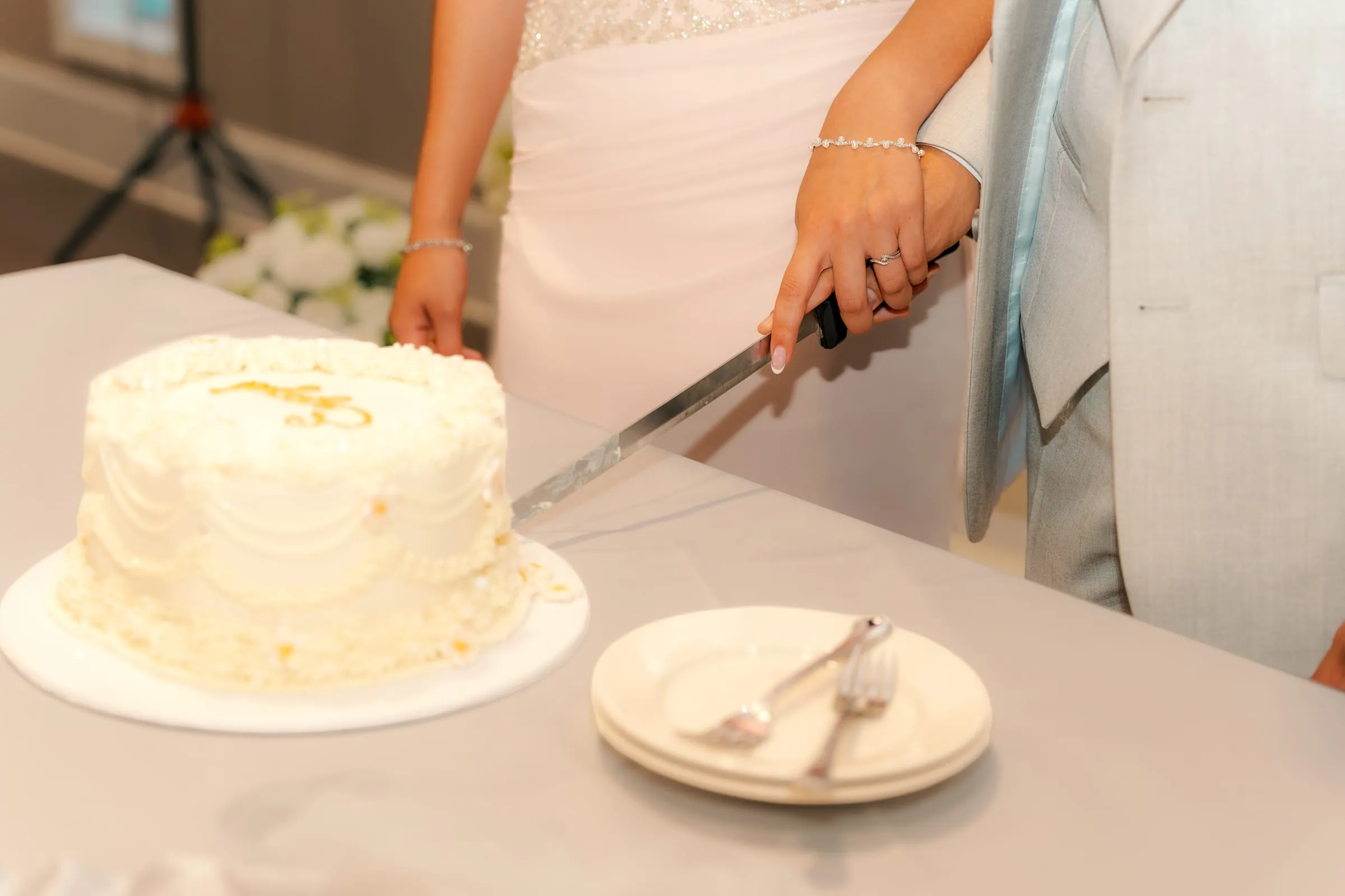 Close-up of Lavina and Youssef's hands cutting into their engagement cake