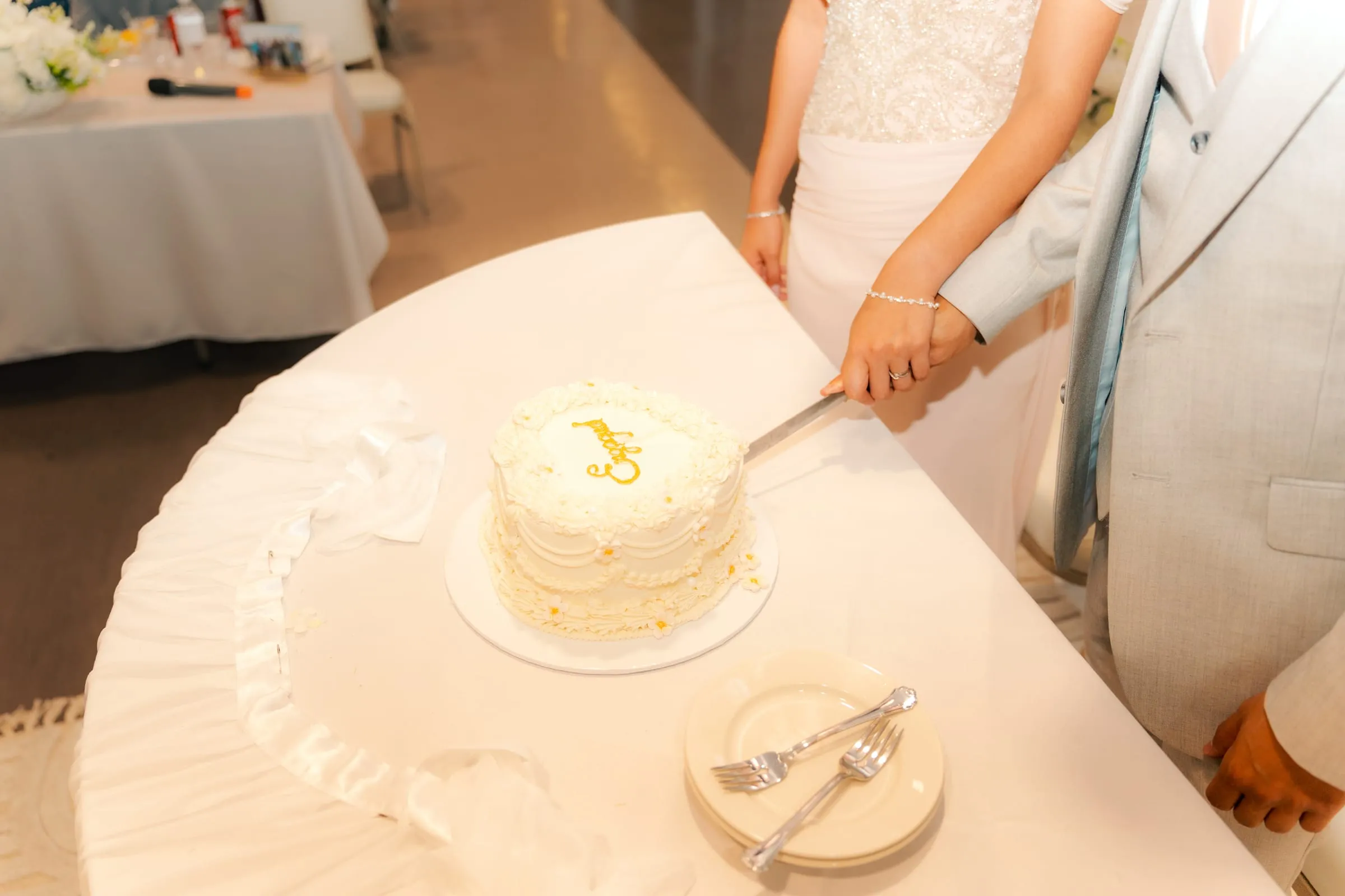 An overhead view of the engagement cake with its gold monogram as Lavina and Youssef cut into it