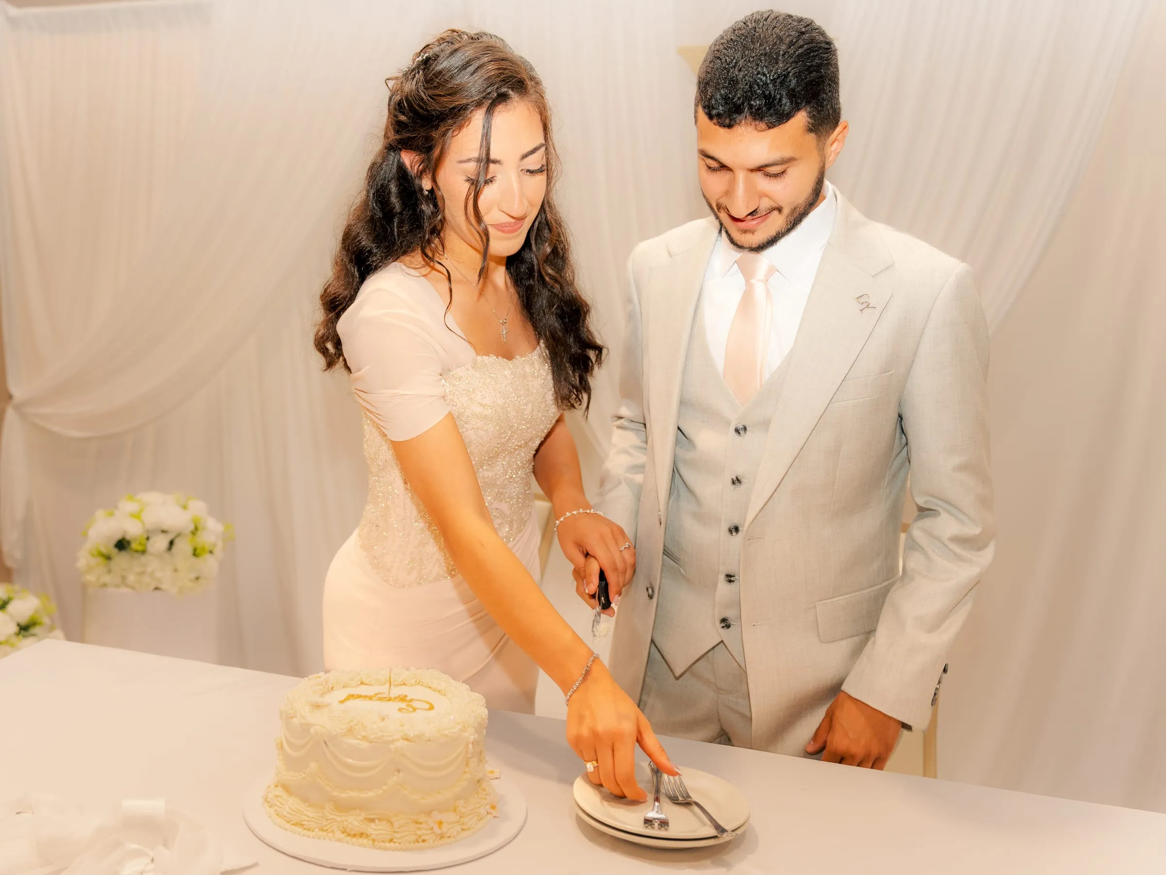Lavina placing a slice of cake on a plate as Youssef smiles beside her