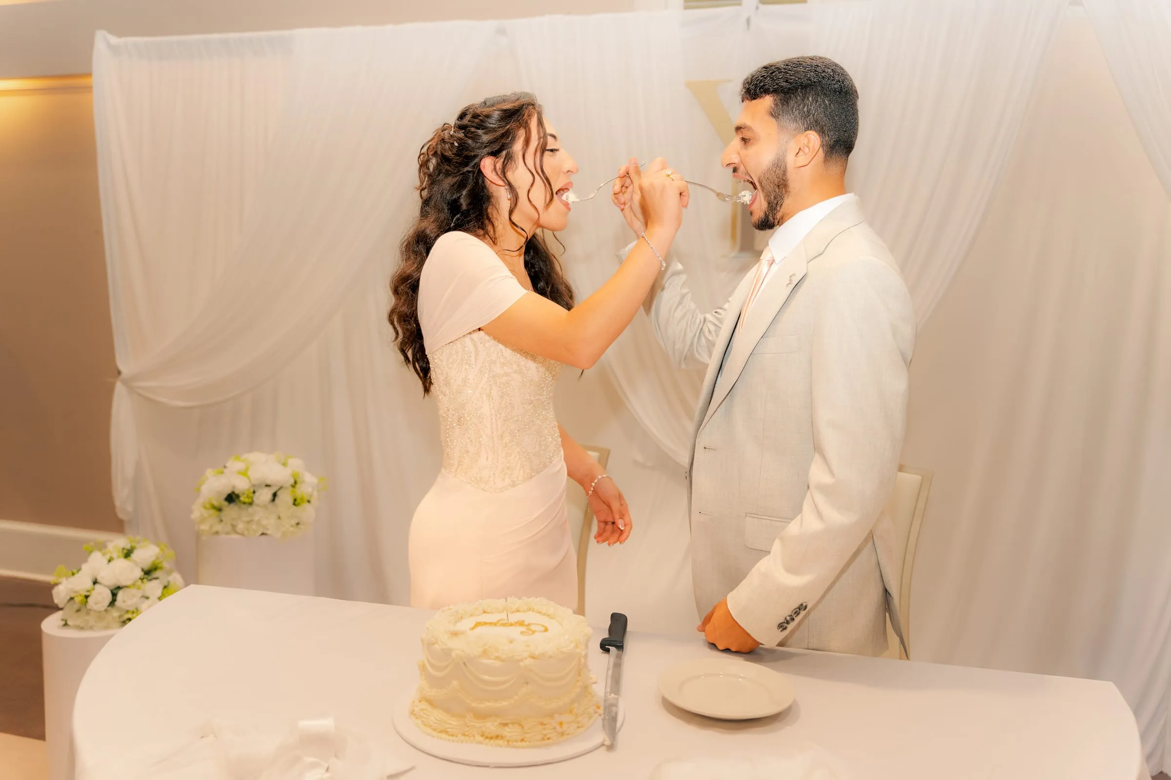 Lavina and Youssef laughing while feeding each other cake