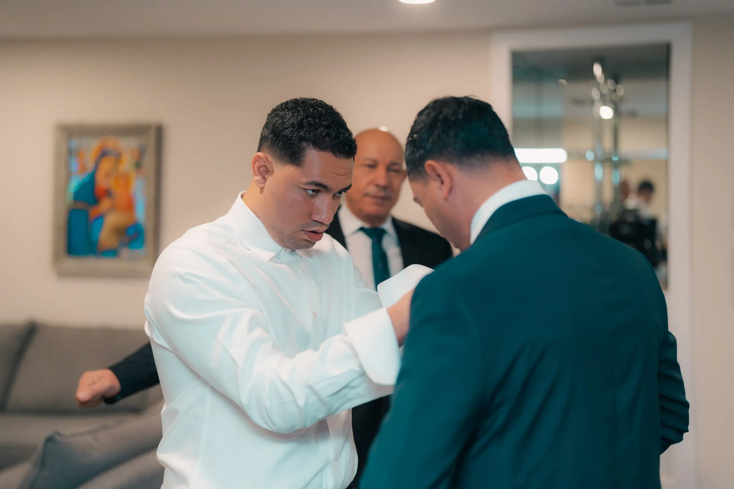 Groomsmen helping each other with cufflinks before Mariam and Mina's wedding