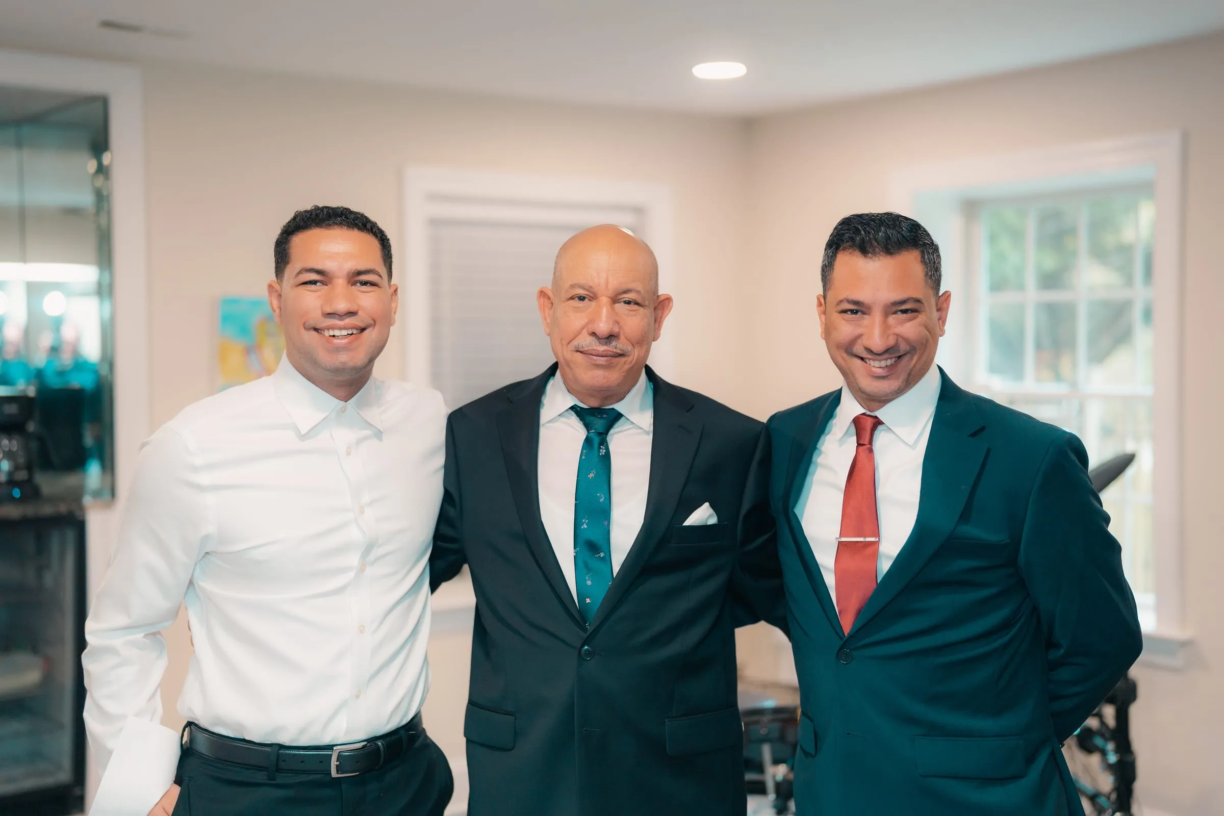 Mina and his groomsmen in teal and navy suits posing together before the ceremony