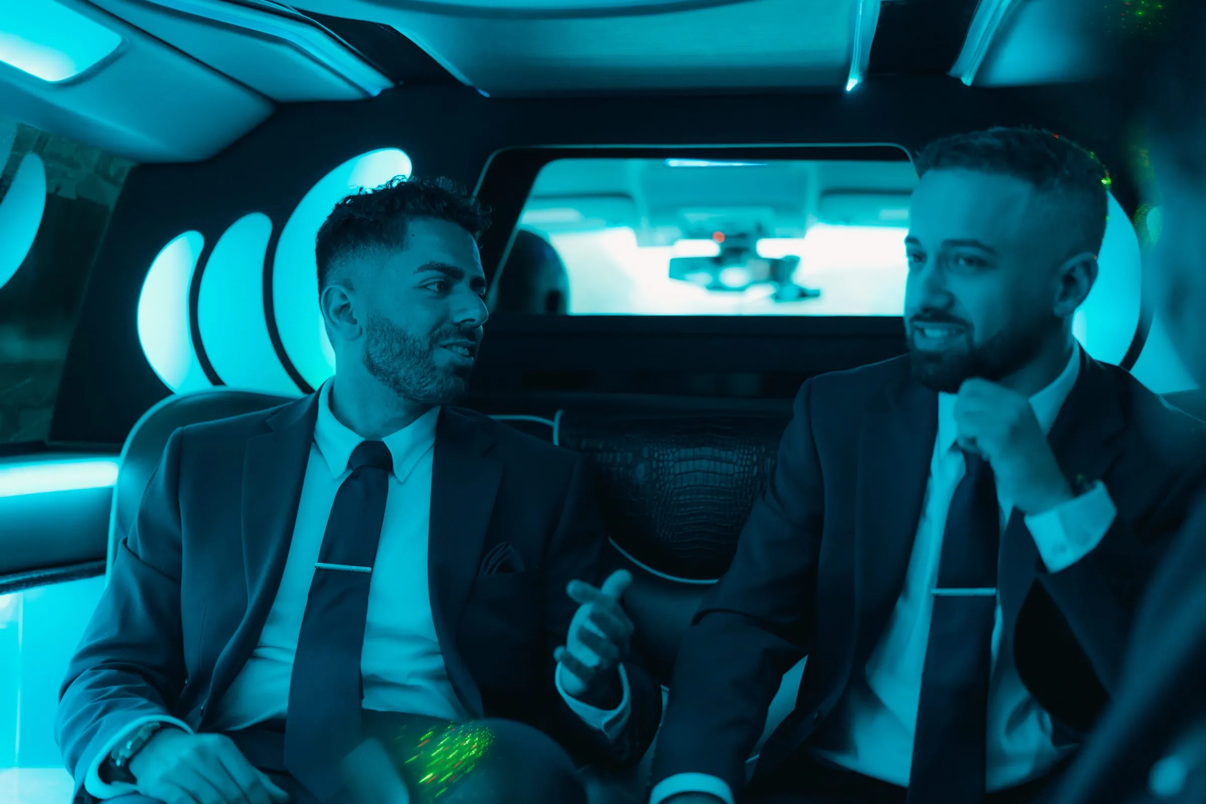 Two groomsmen talking together inside the wedding limo on the way