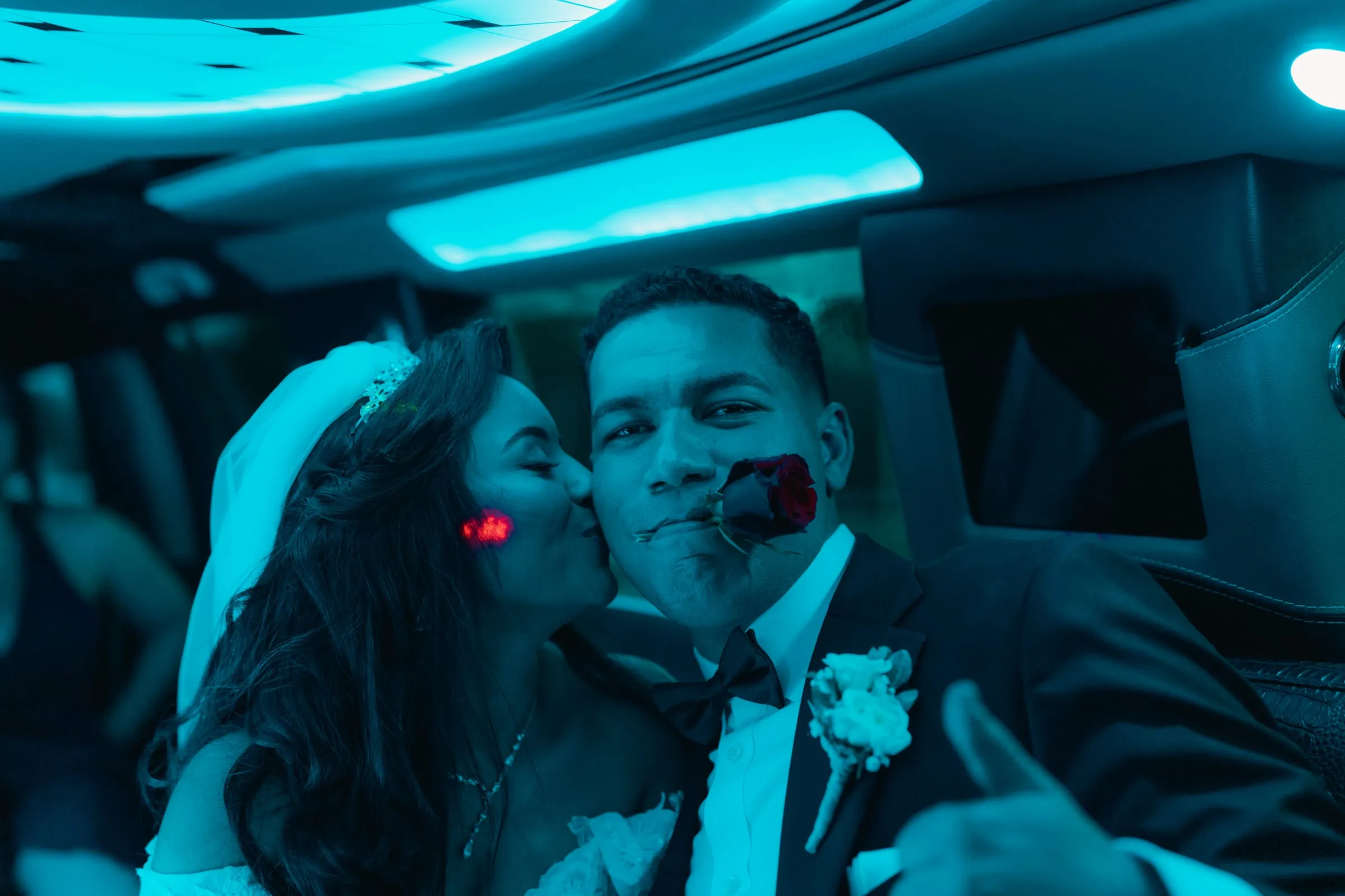 Mariam kissing Mina's cheek inside the limo, a rose held between his teeth