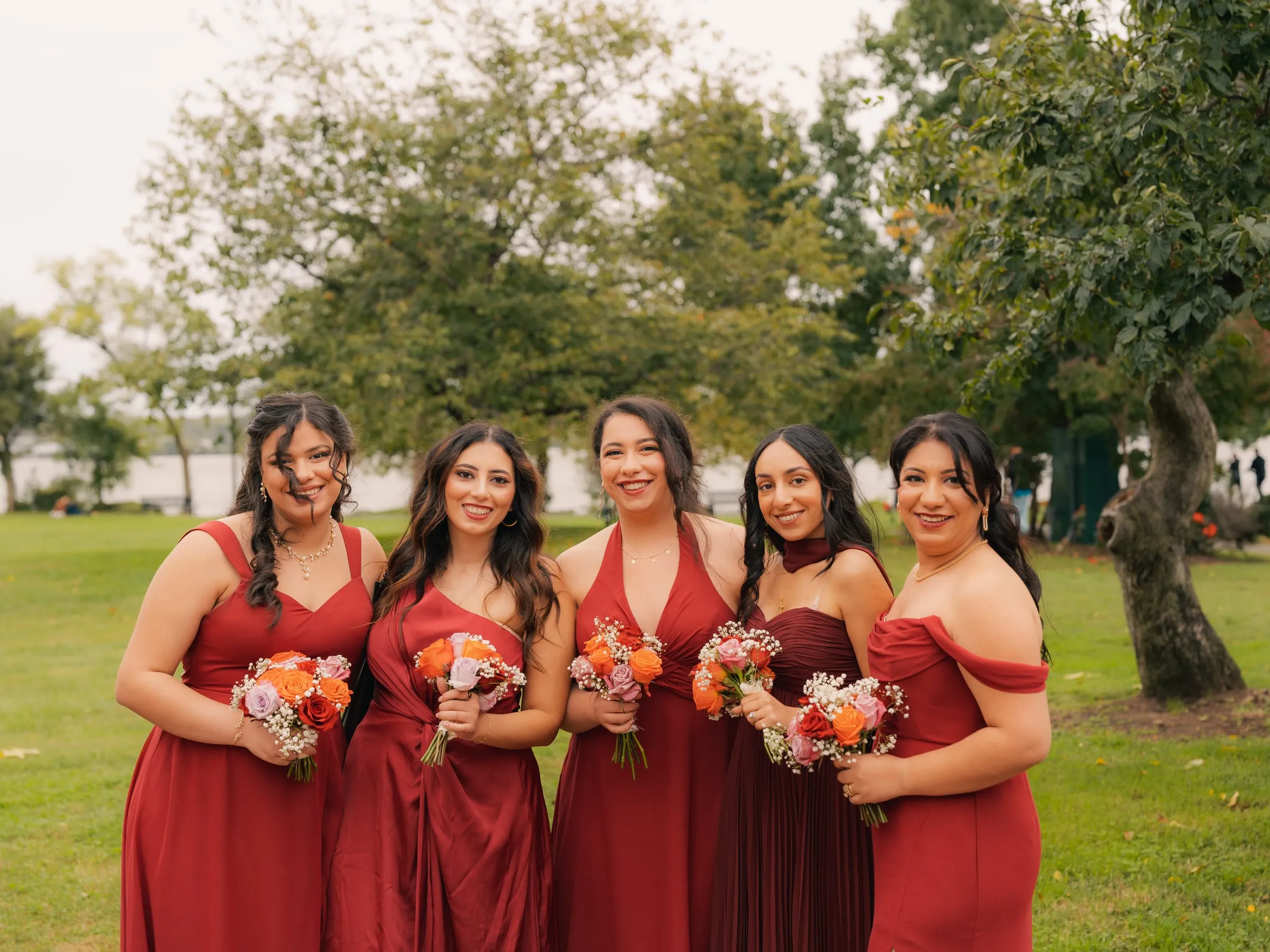 Five bridesmaids posing together with their bouquets by the water