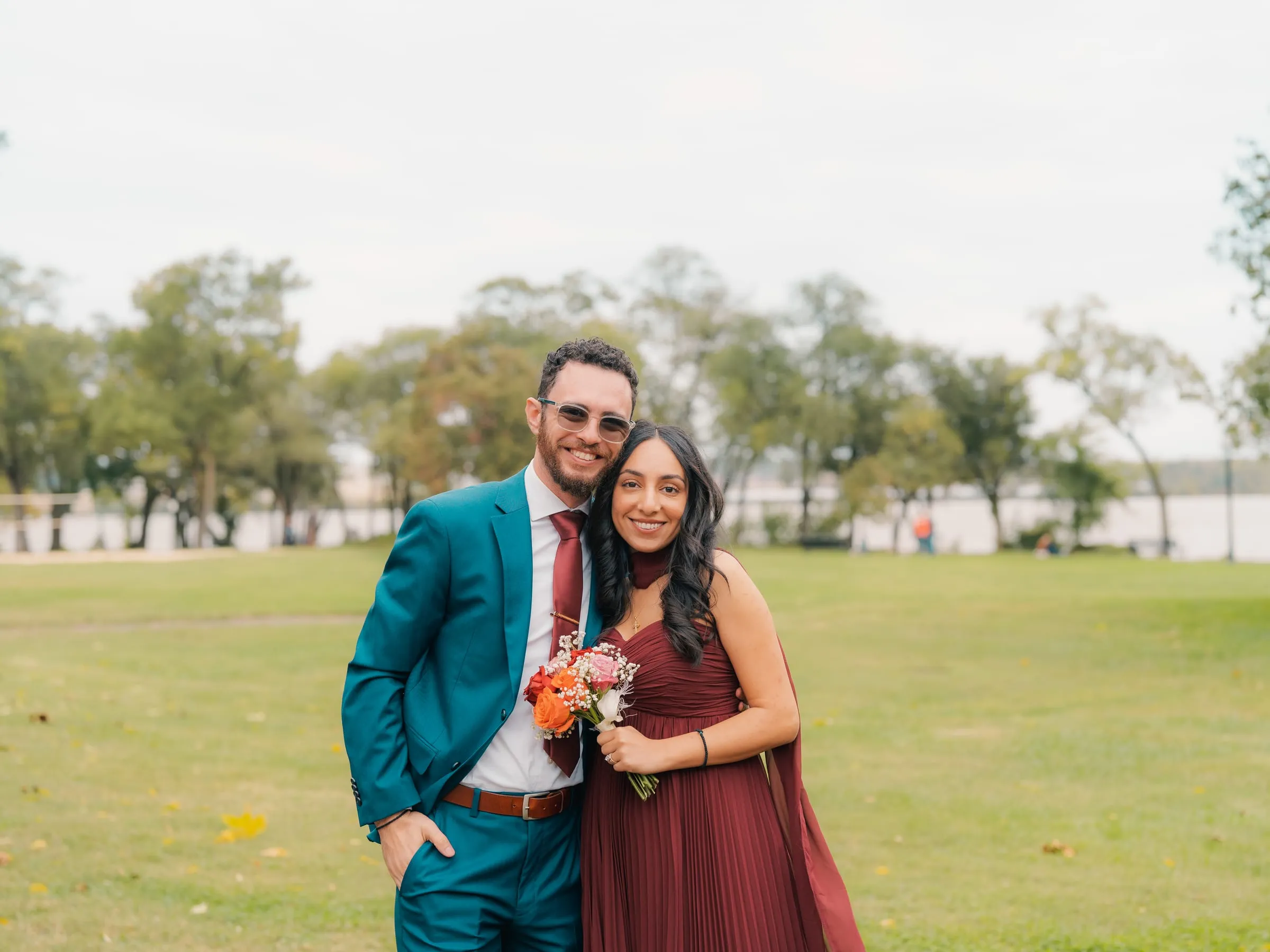 A groomsman in sunglasses and a bridesmaid sharing a quiet moment together in the park