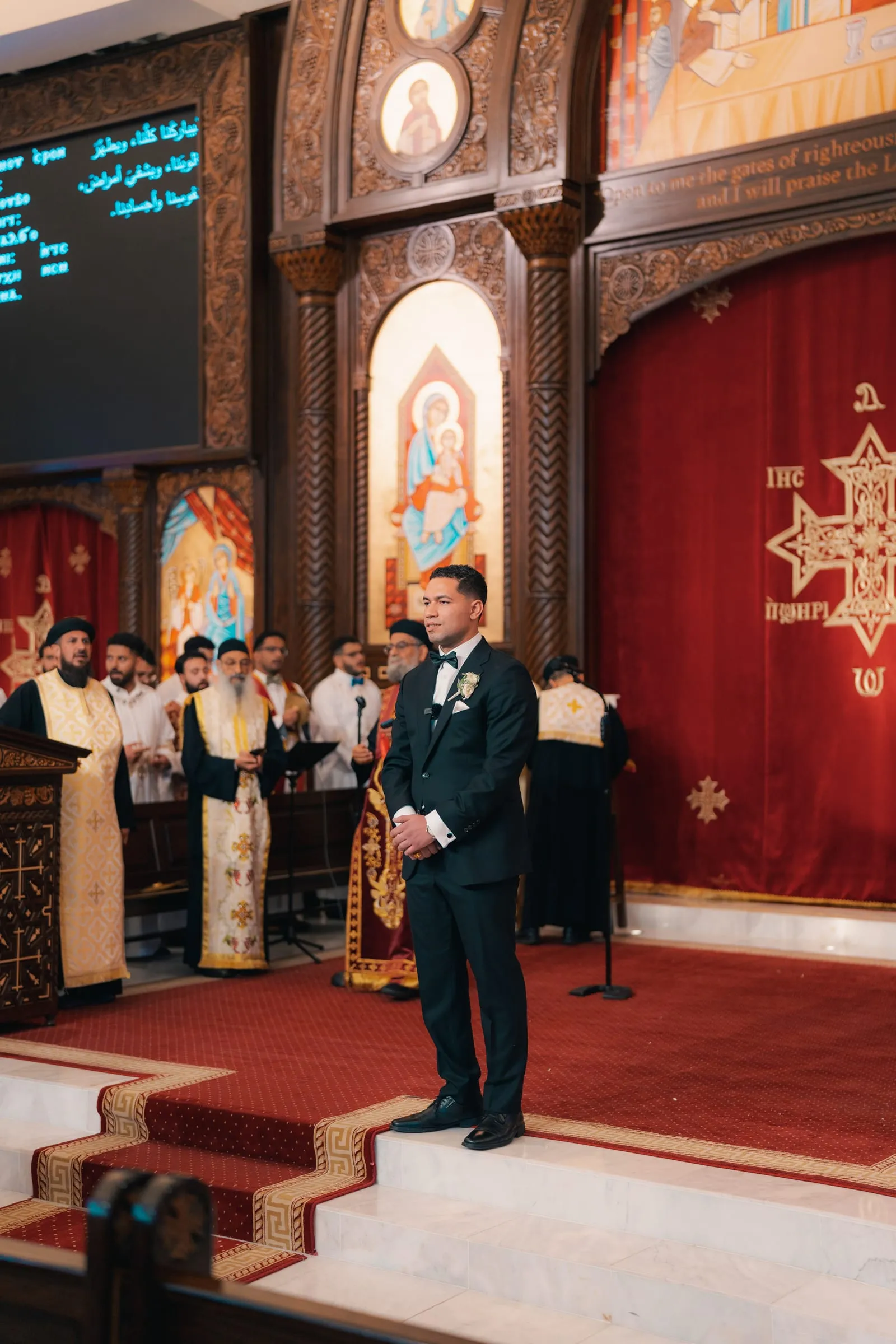 Mina standing at the altar as the church choir and clergy sing behind him