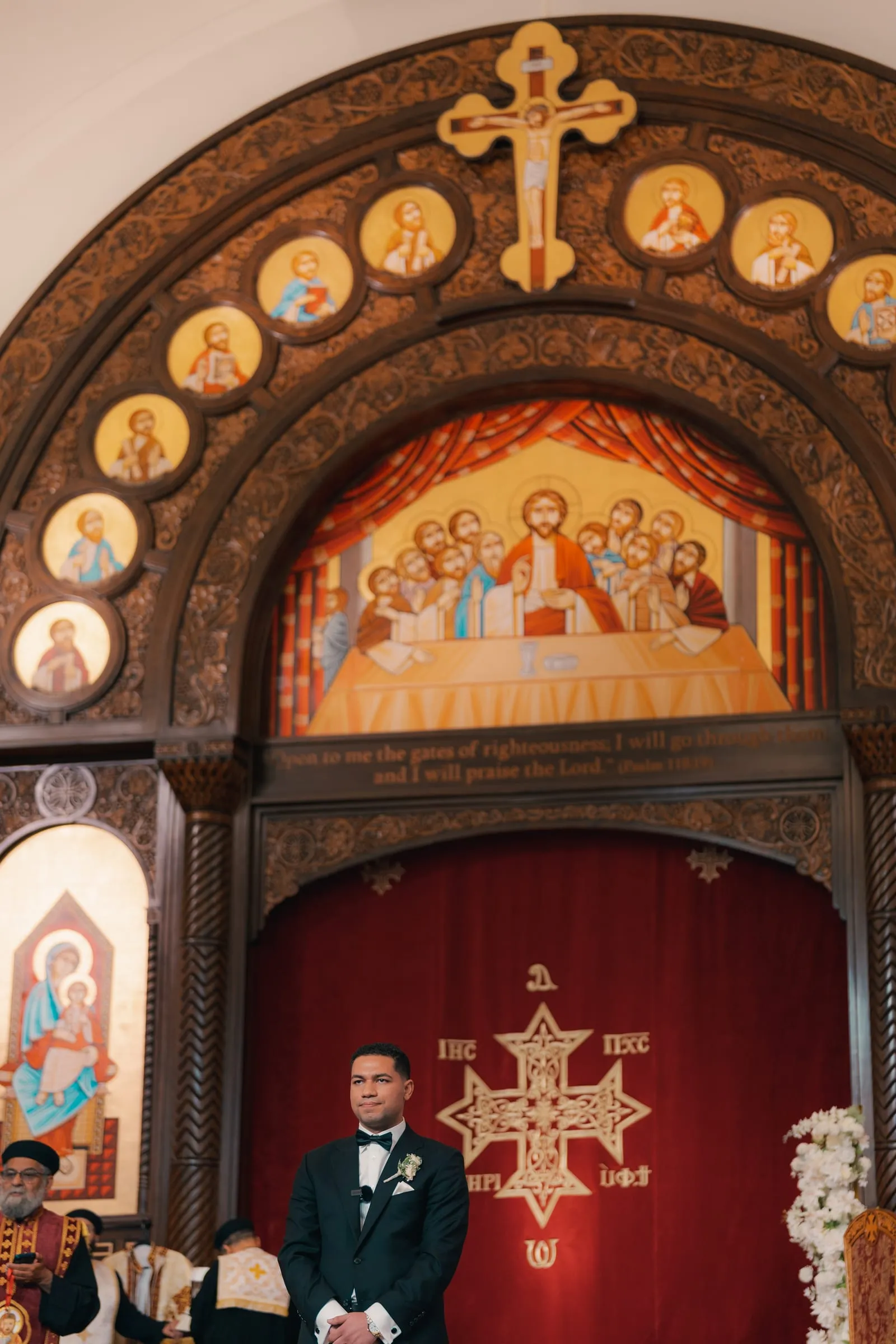 Mina standing beneath the church's carved arch and icon of the Last Supper during the wedding service