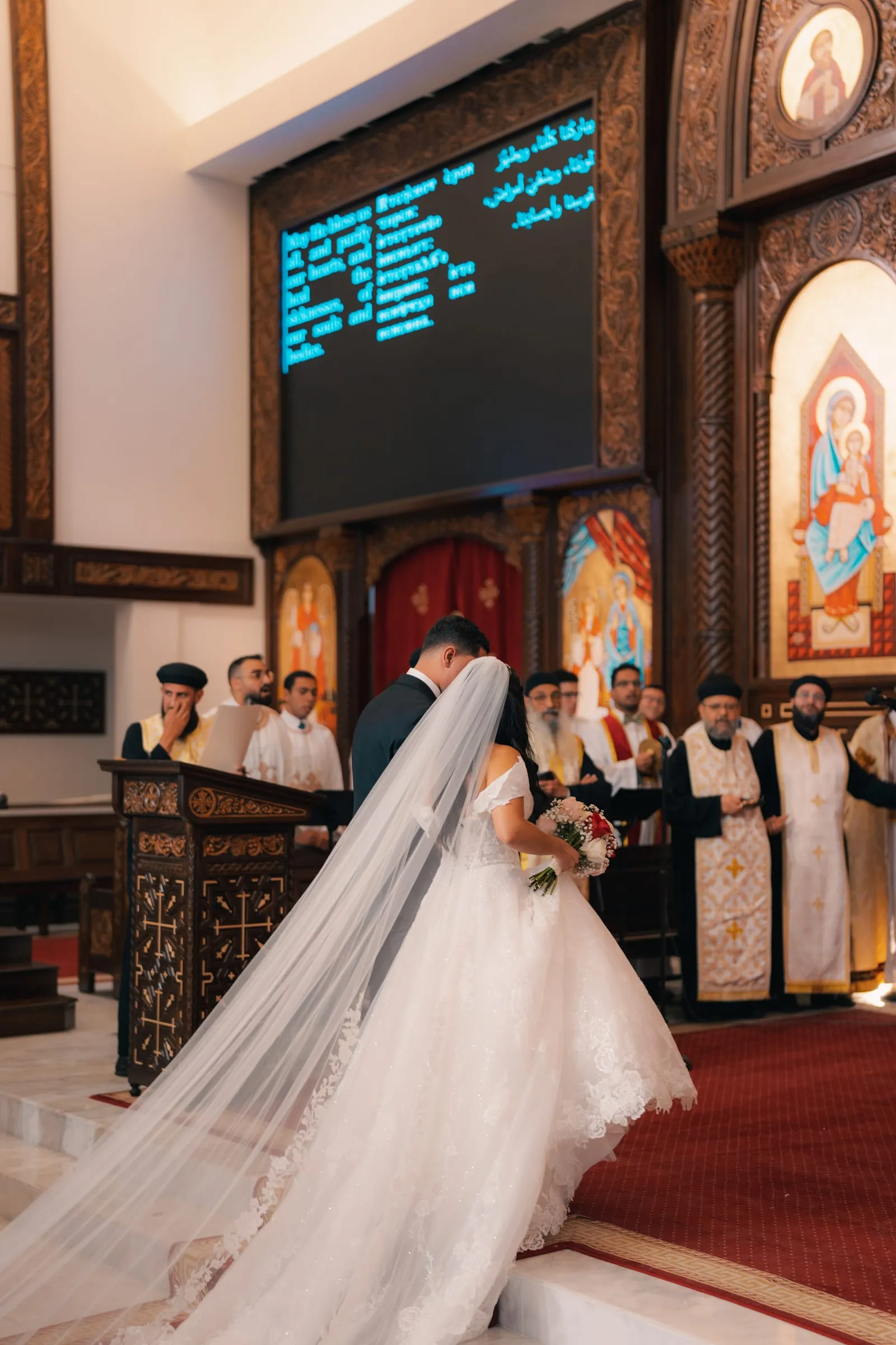 Mariam and Mina walking toward the altar together, her veil trailing behind her