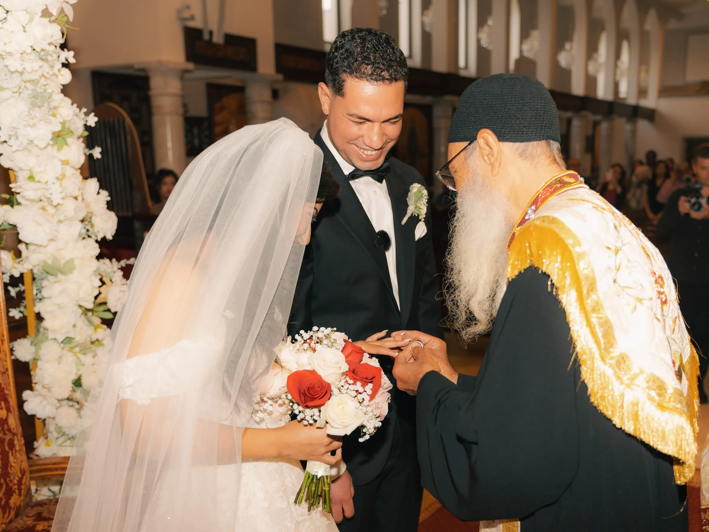 The priest placing the ring on Mariam's finger during the wedding ceremony
