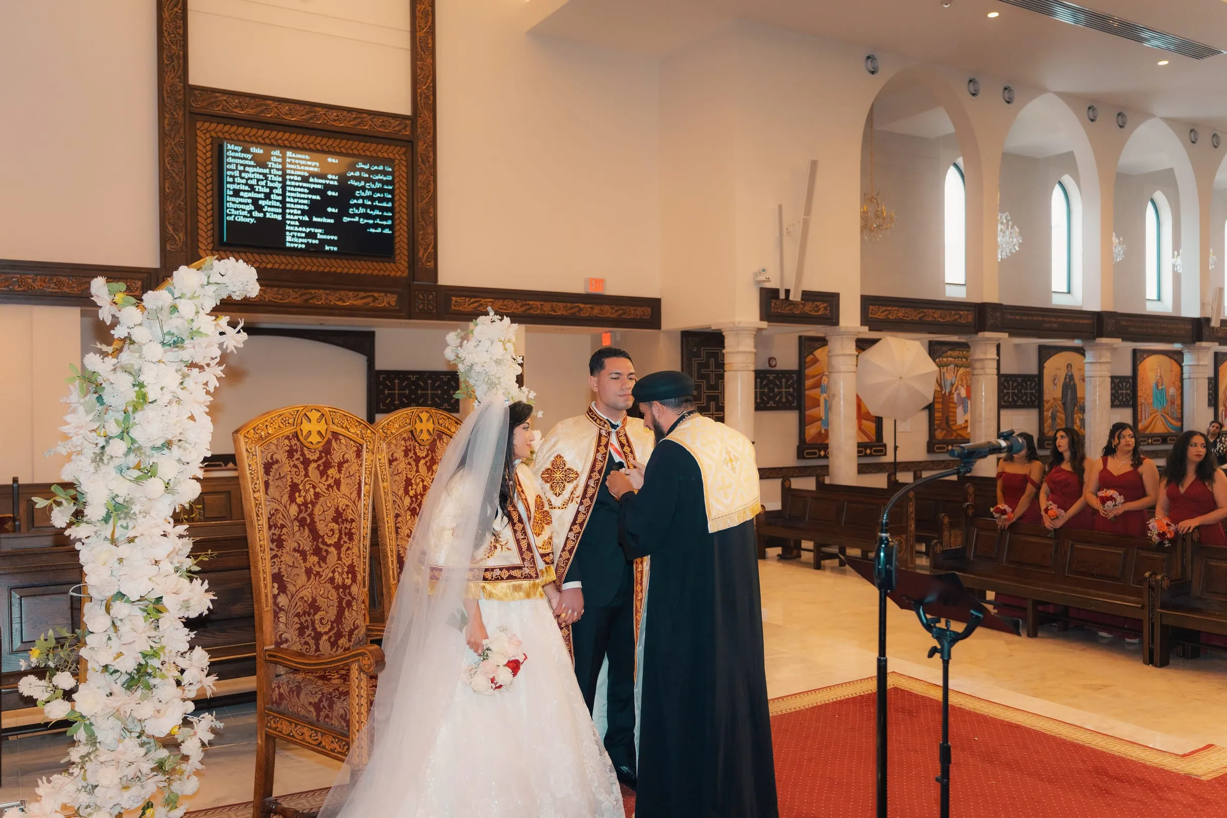 The priest placing the ceremonial stole over Mina's shoulders during the crowning rite