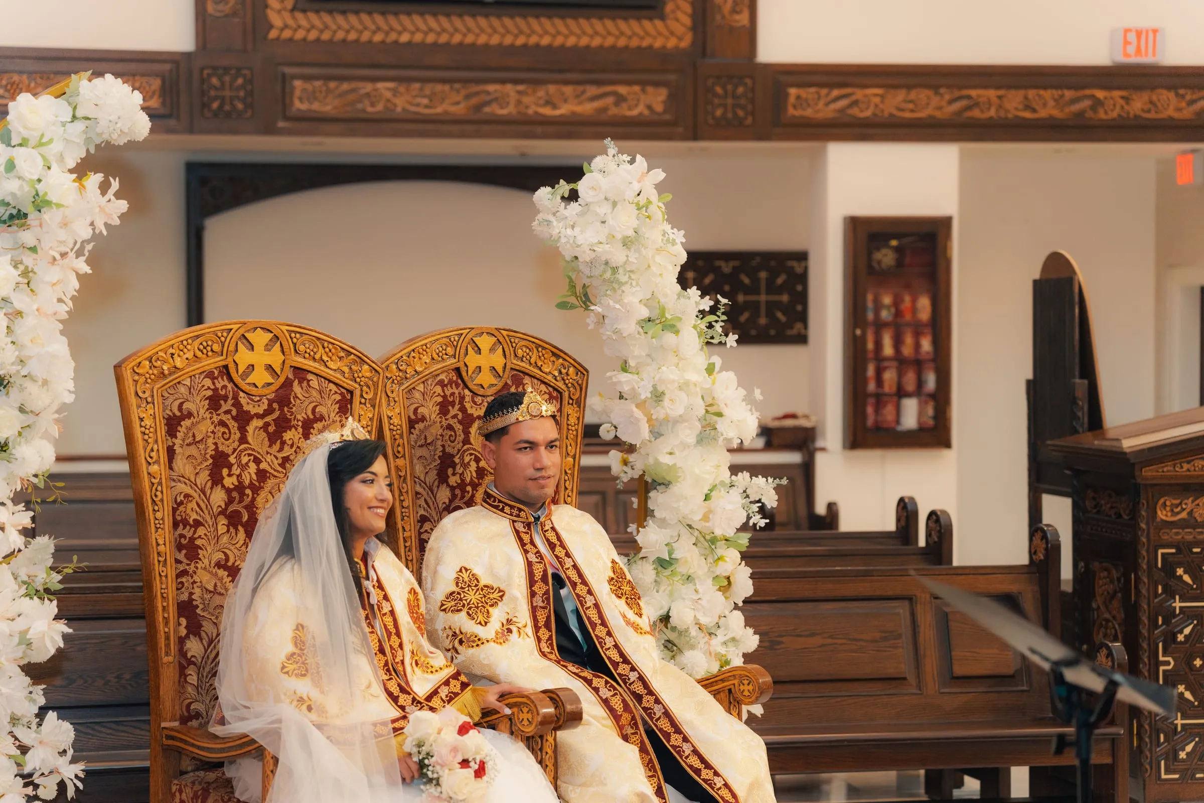 Mariam and Mina seated on the ornate wedding thrones wearing their ceremonial crowns