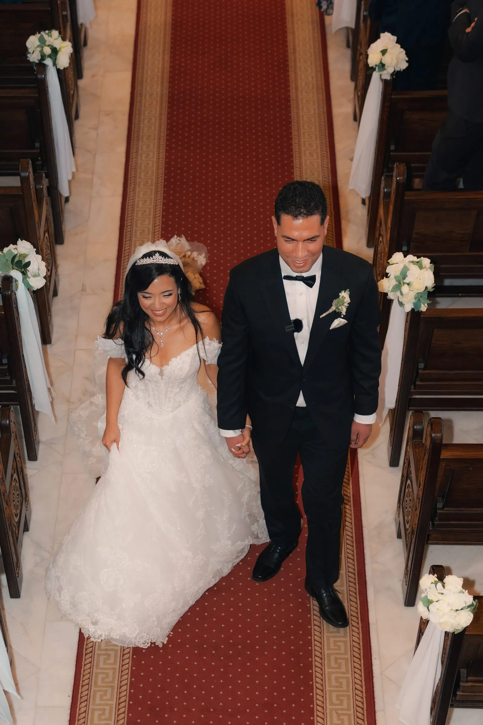 Mariam and Mina recessing down the aisle past guests and floral pew markers