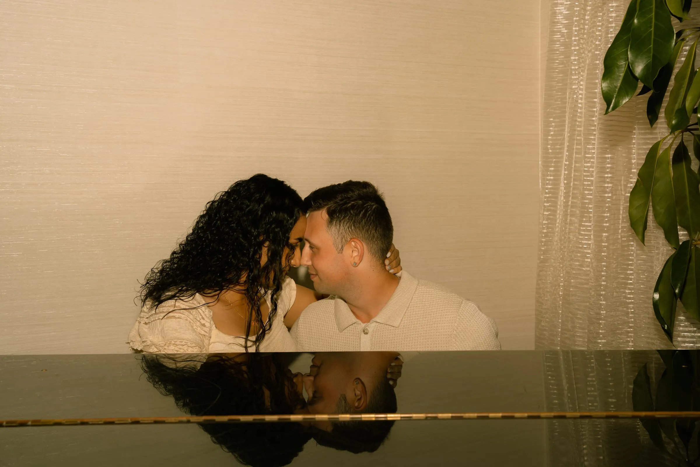 Mariam and Thomas leaning together over a grand piano, foreheads touching, at the Westfields Marriott