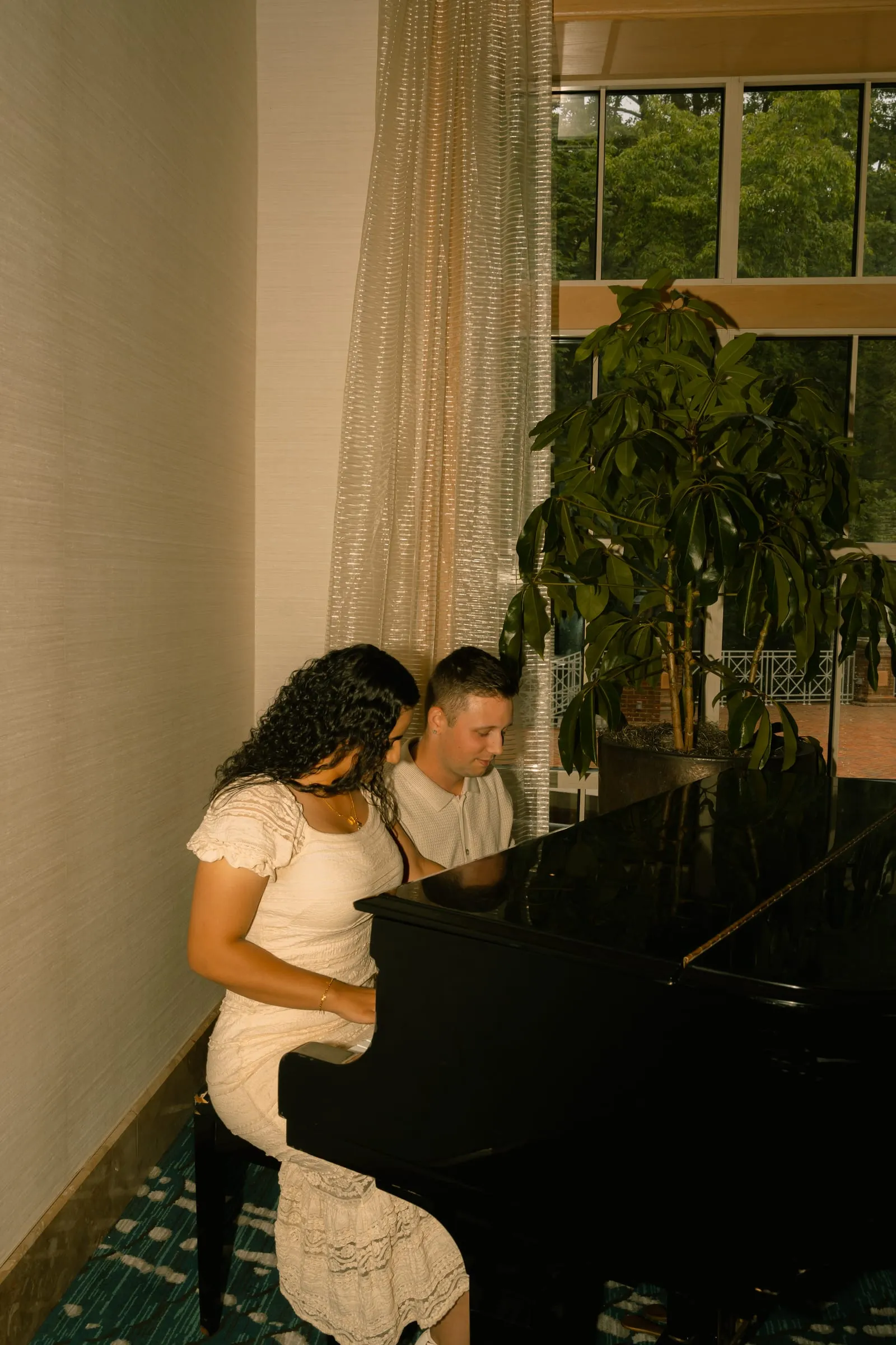 Mariam and Thomas seated at the piano beside a window overlooking the garden
