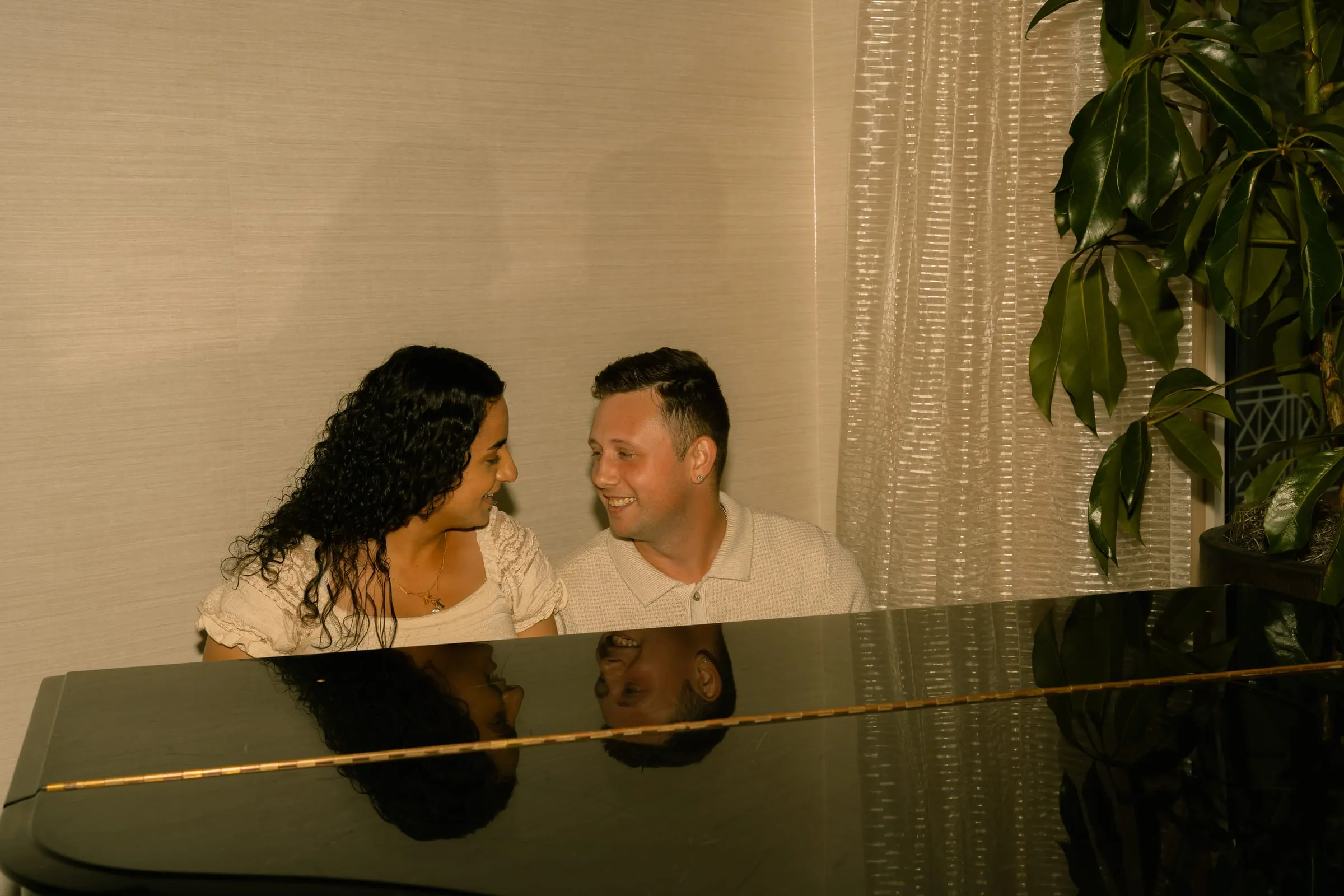 Mariam and Thomas smiling at each other at the piano