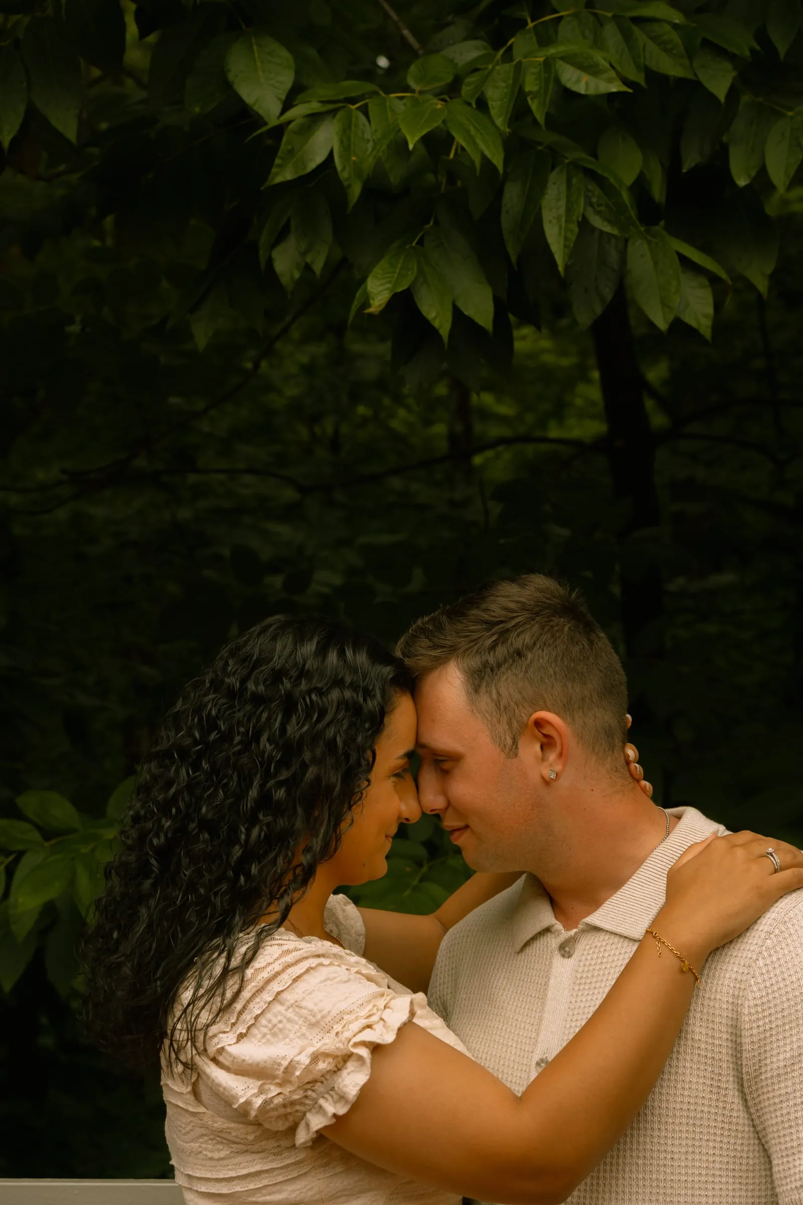 Mariam and Thomas standing close together under the tree canopy