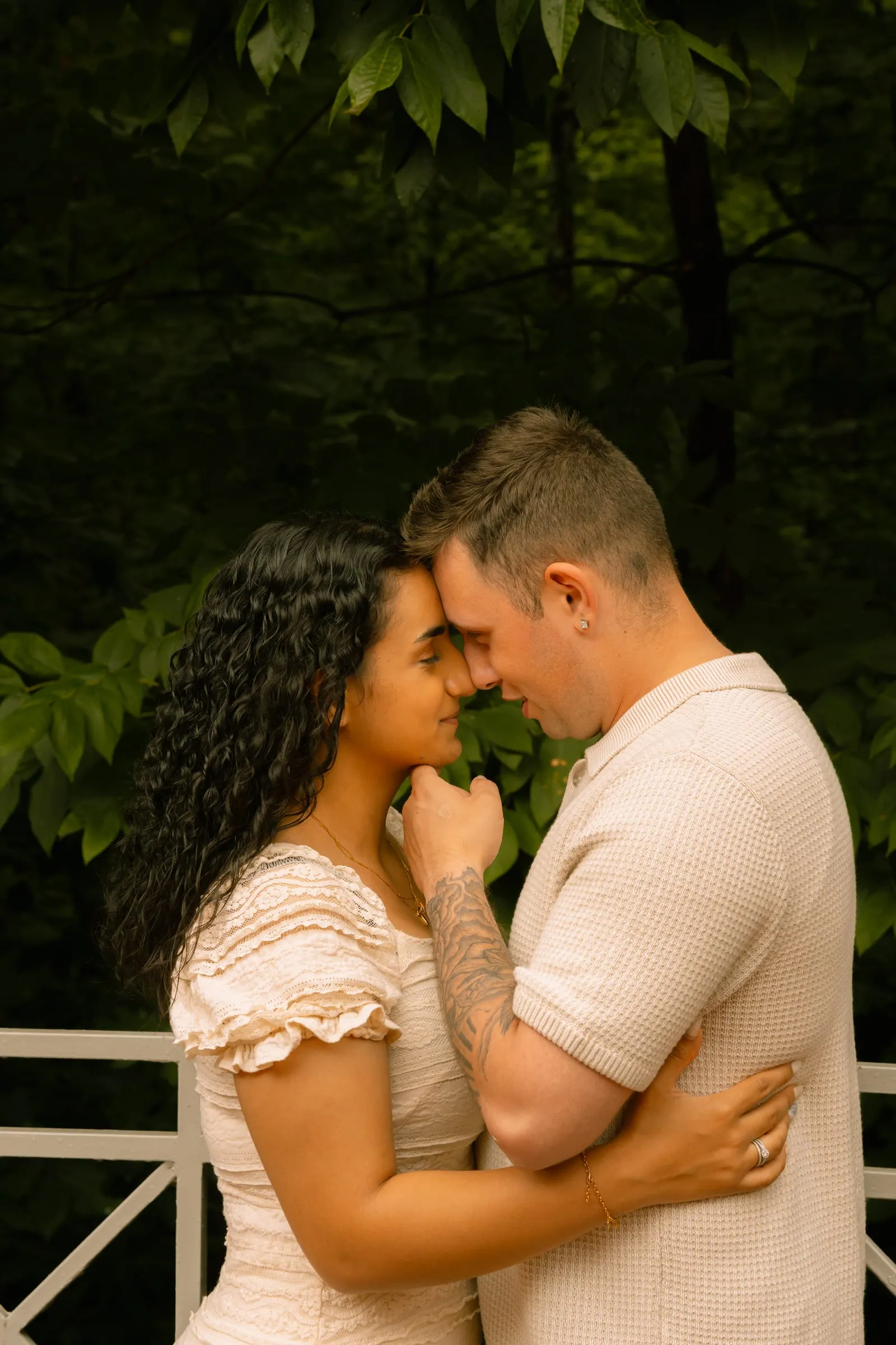 Thomas lifting Mariam's chin in a quiet moment beside the garden railing