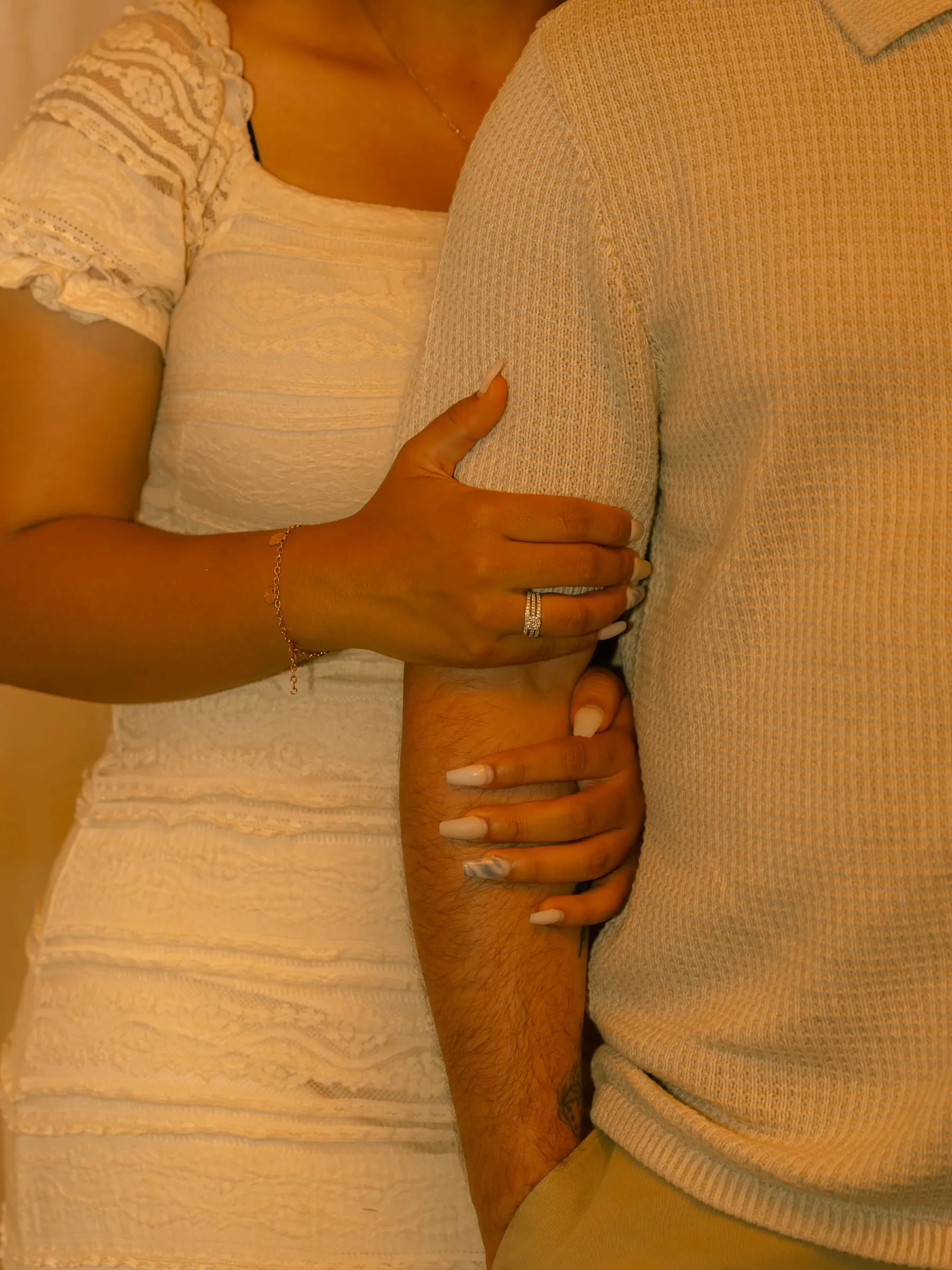 Close-up of Mariam's hand on Thomas's arm, her engagement ring and bracelet visible