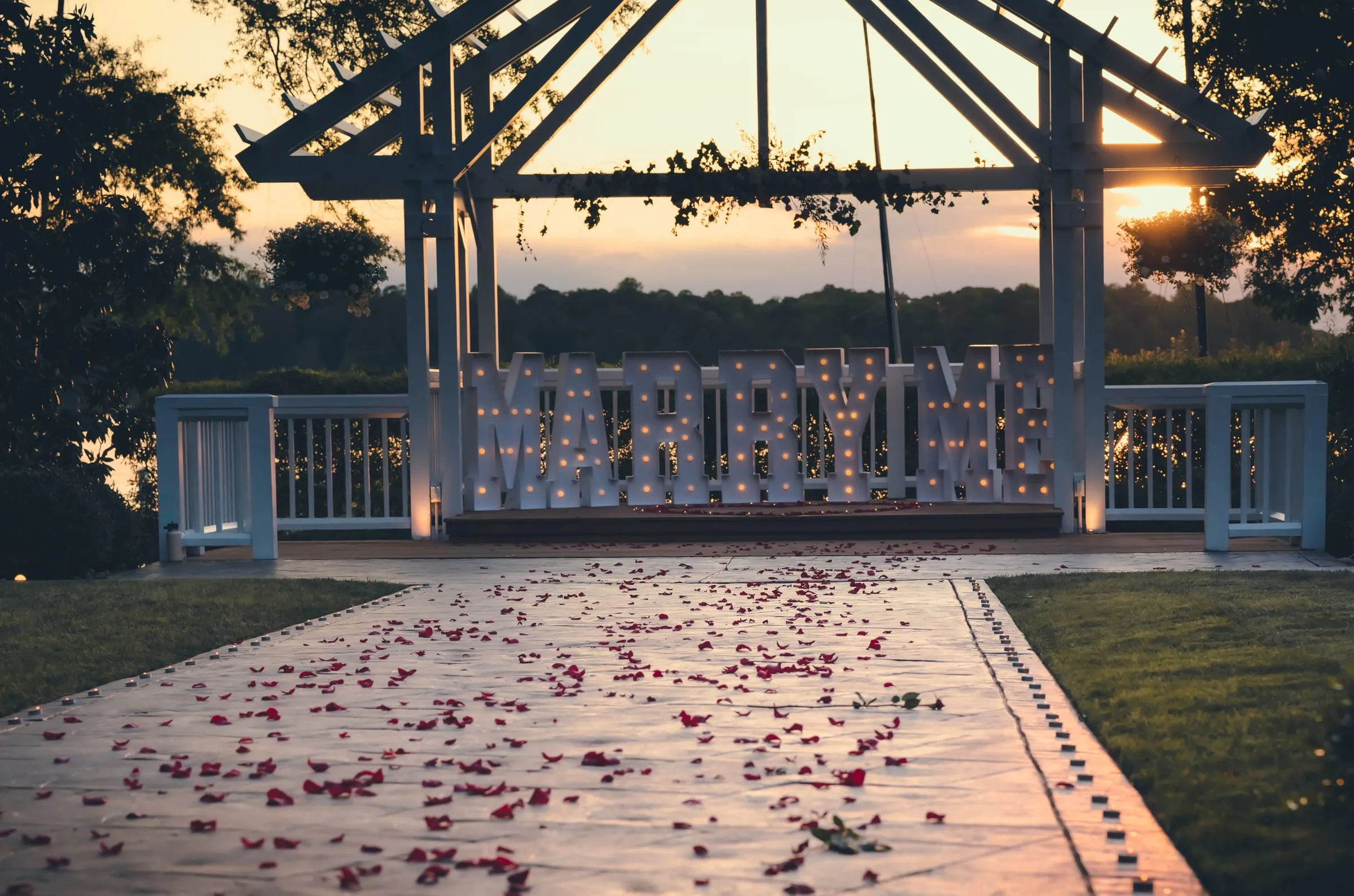 A wide view of the rose petal path and the glowing MARRY ME sign at the Boathouse at Sunday Park