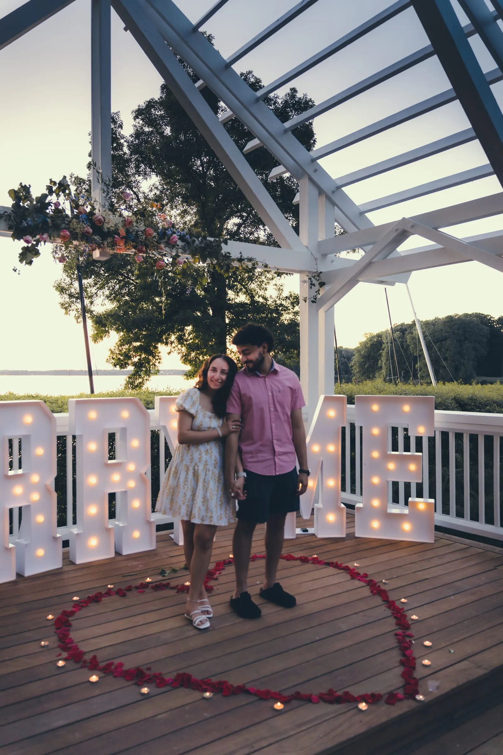 Marina and George standing in the rose petal heart inside the pavilion, surrounded by the glowing letters