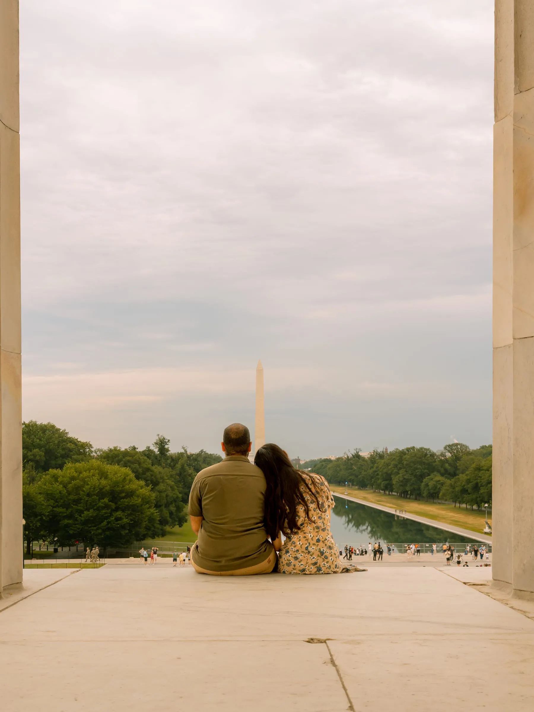 Maryann and Samuel sitting on the steps of the Lincoln Memorial, looking out at the Washington Monument and Reflecting Pool