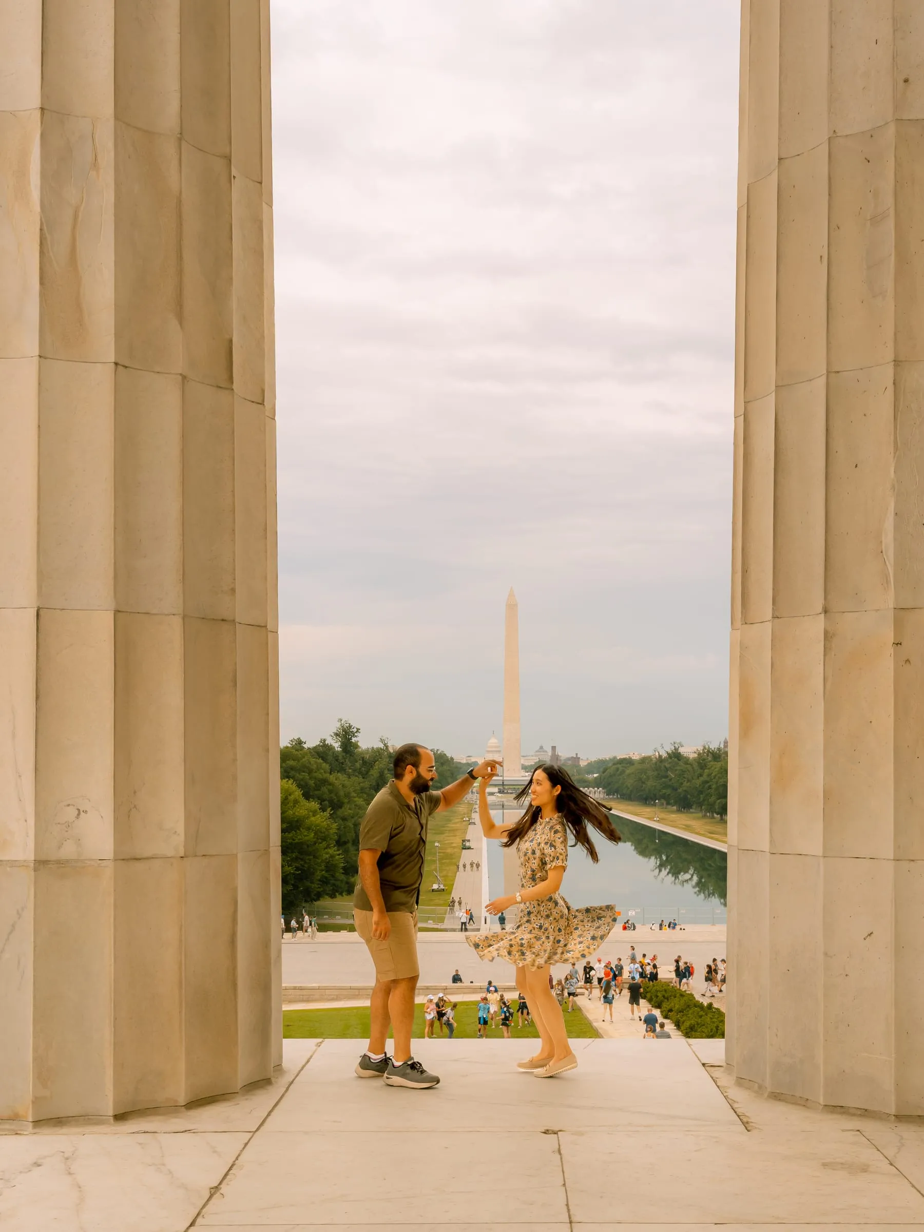 Samuel twirling Maryann between the columns of the Lincoln Memorial, the Washington Monument behind them