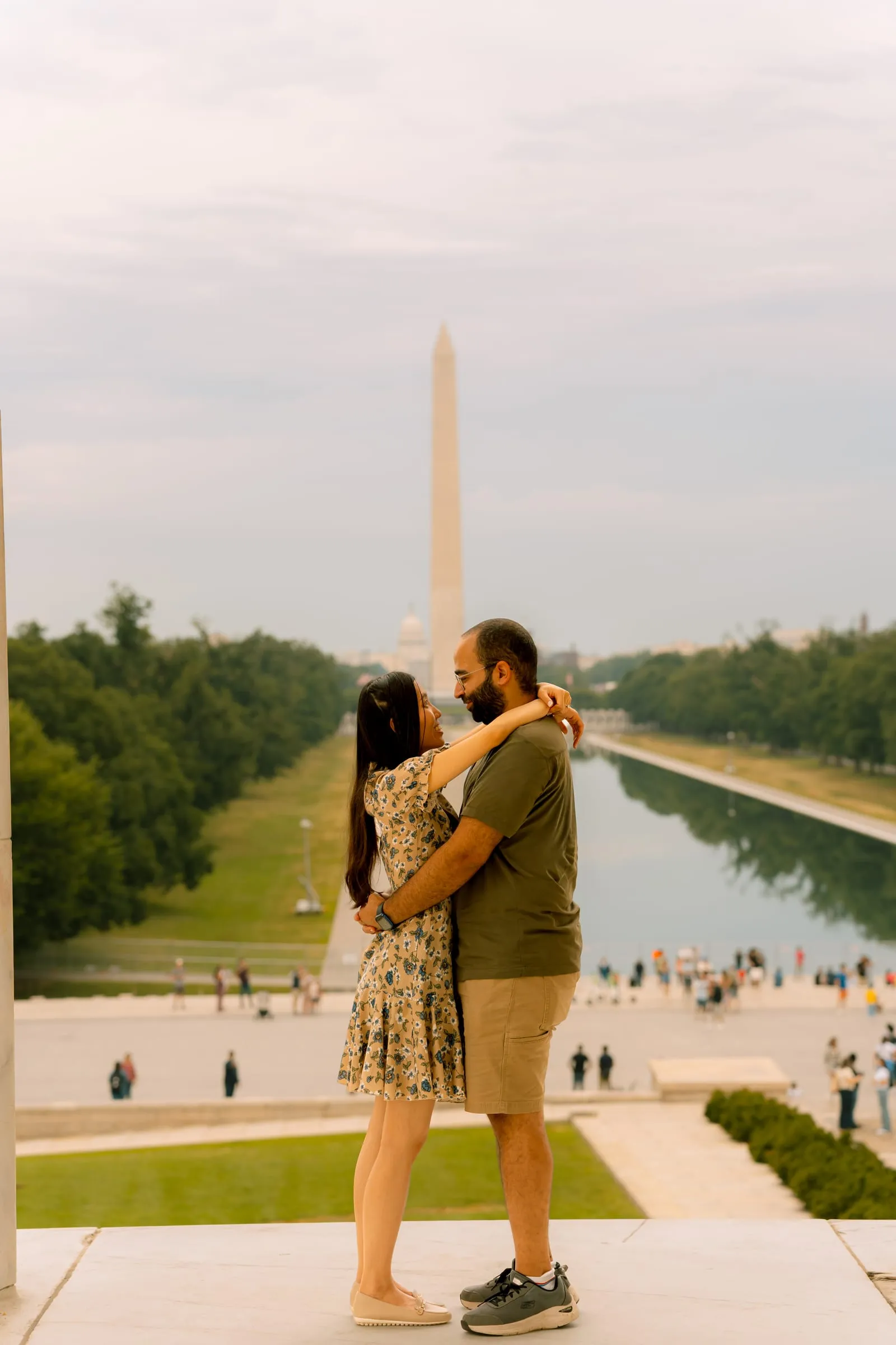 Maryann and Samuel holding each other close, the Washington Monument and Reflecting Pool behind them