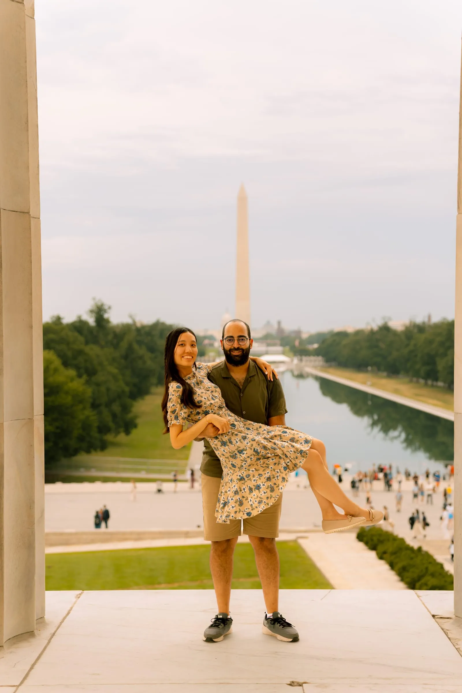 Samuel carrying Maryann in his arms at the top of the Lincoln Memorial steps, the Washington Monument behind them